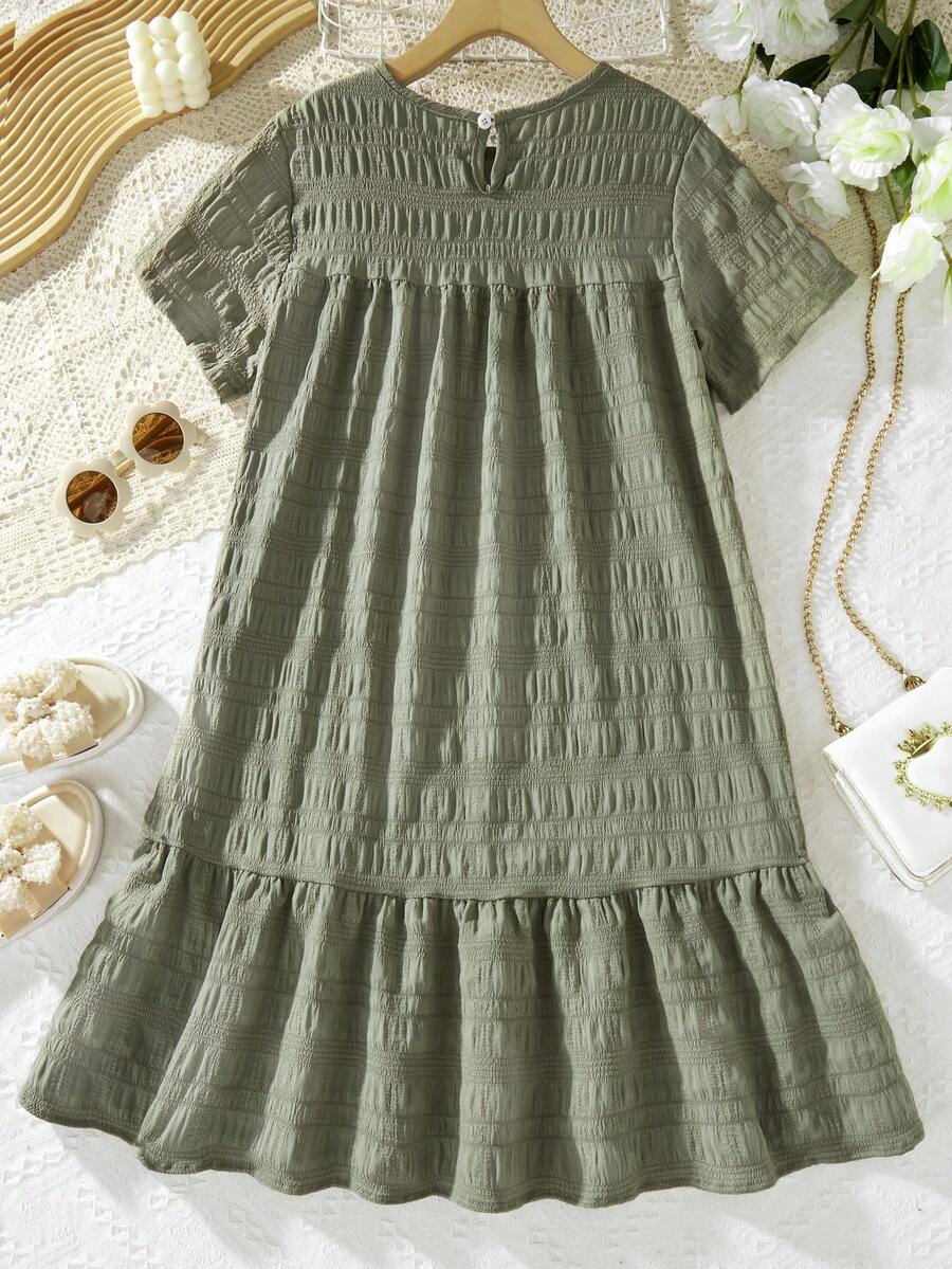 Tween girl wearing an Army Green textured short sleeve smock midi dress with round neck and ruffle flounce hem.