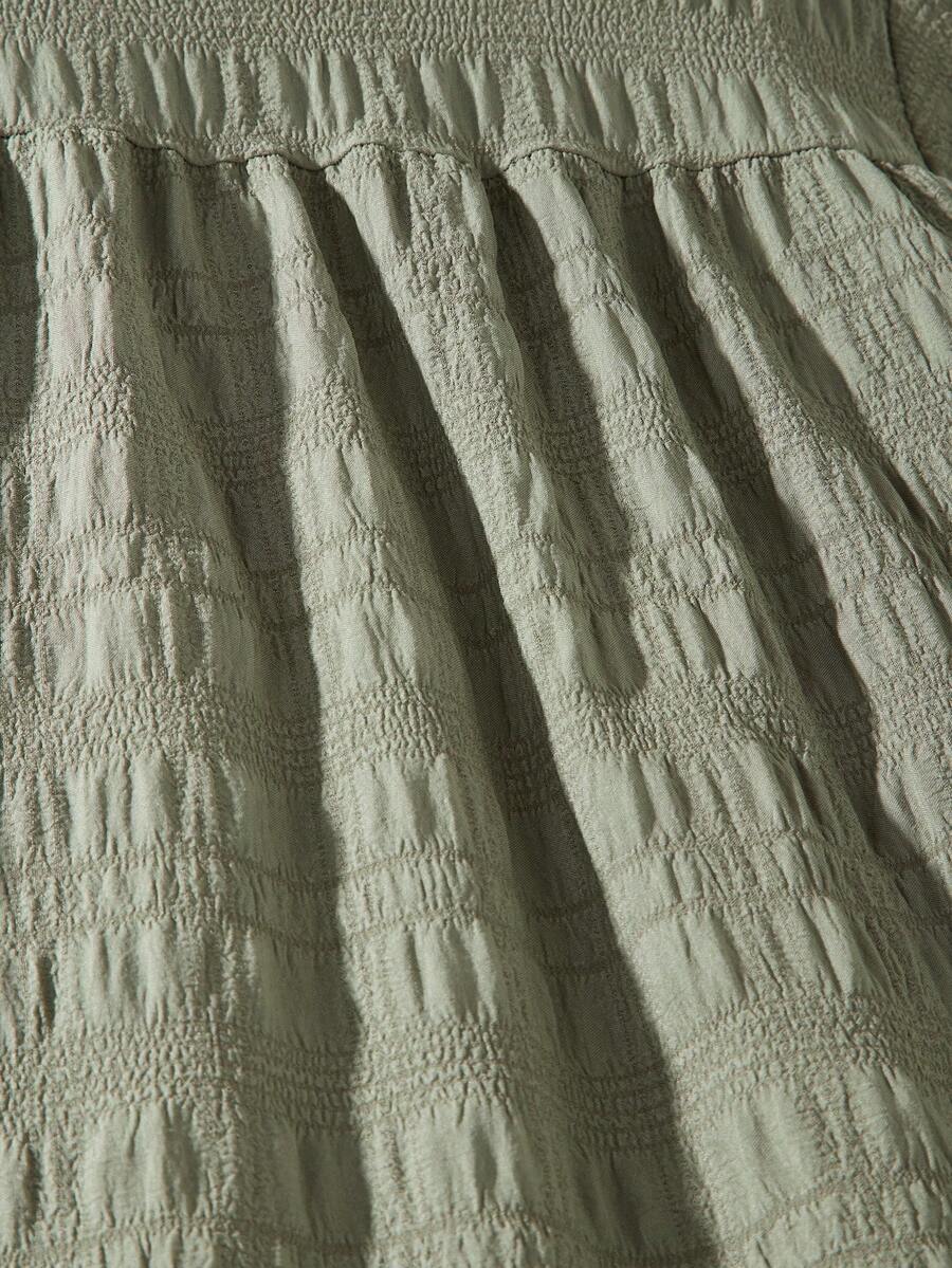 Tween girl wearing an Army Green textured short sleeve smock midi dress with round neck and ruffle flounce hem.