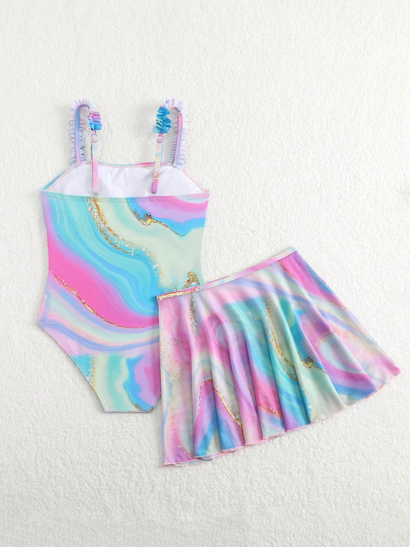 Blue tween girls one-piece swimsuit with tropical plant print, spaghetti straps, ruffle detail, and skirt-style mid-waist bottom for beach and pool wear.