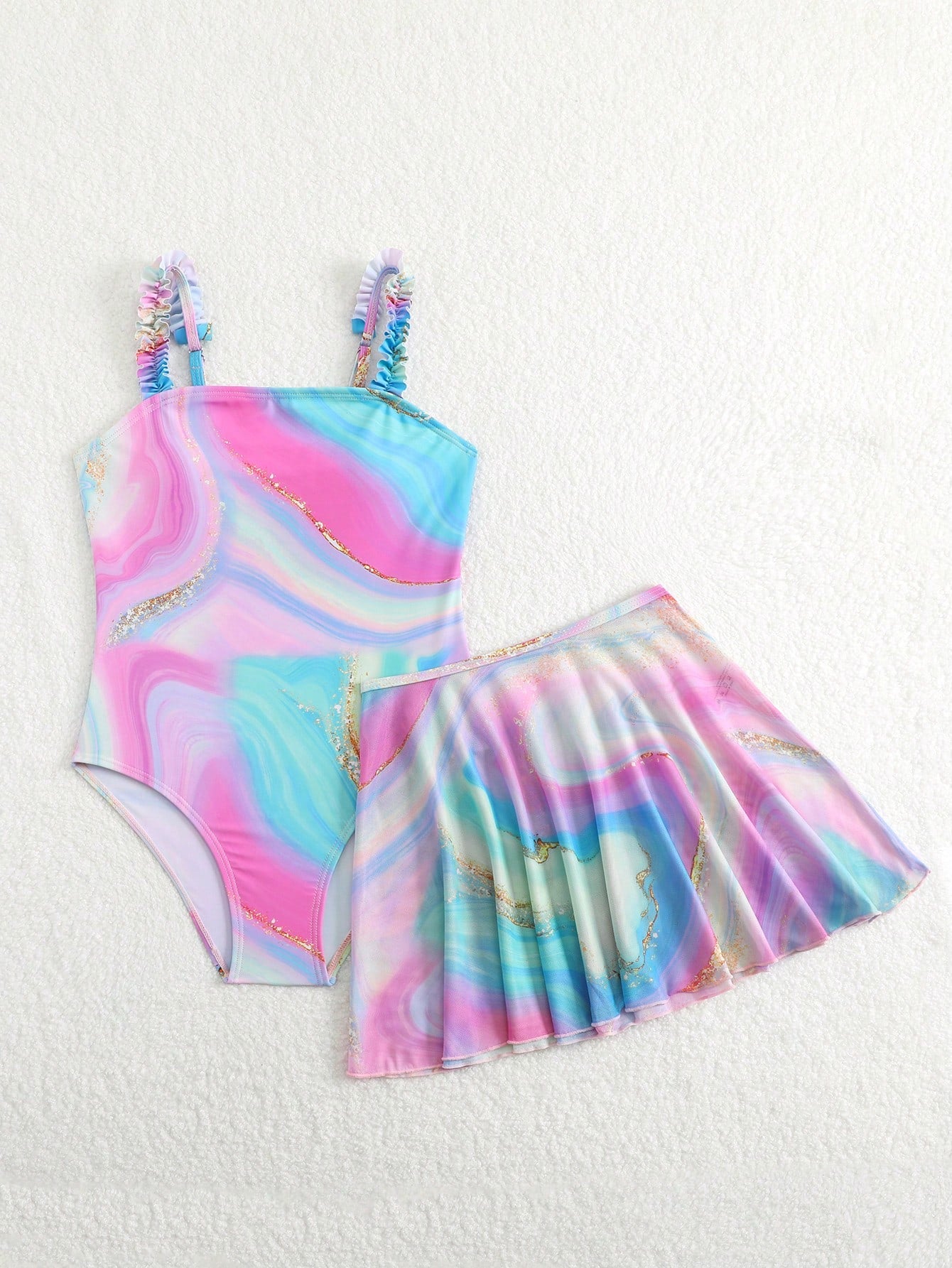 Blue tween girls one-piece swimsuit with tropical plant print, spaghetti straps, ruffle detail, and skirt-style mid-waist bottom for beach and pool wear.
