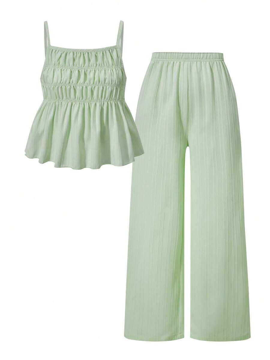 Tween girl wearing an apricot 2-piece outfit set featuring a shirred spaghetti strap short cami top and matching wide-leg long pants.