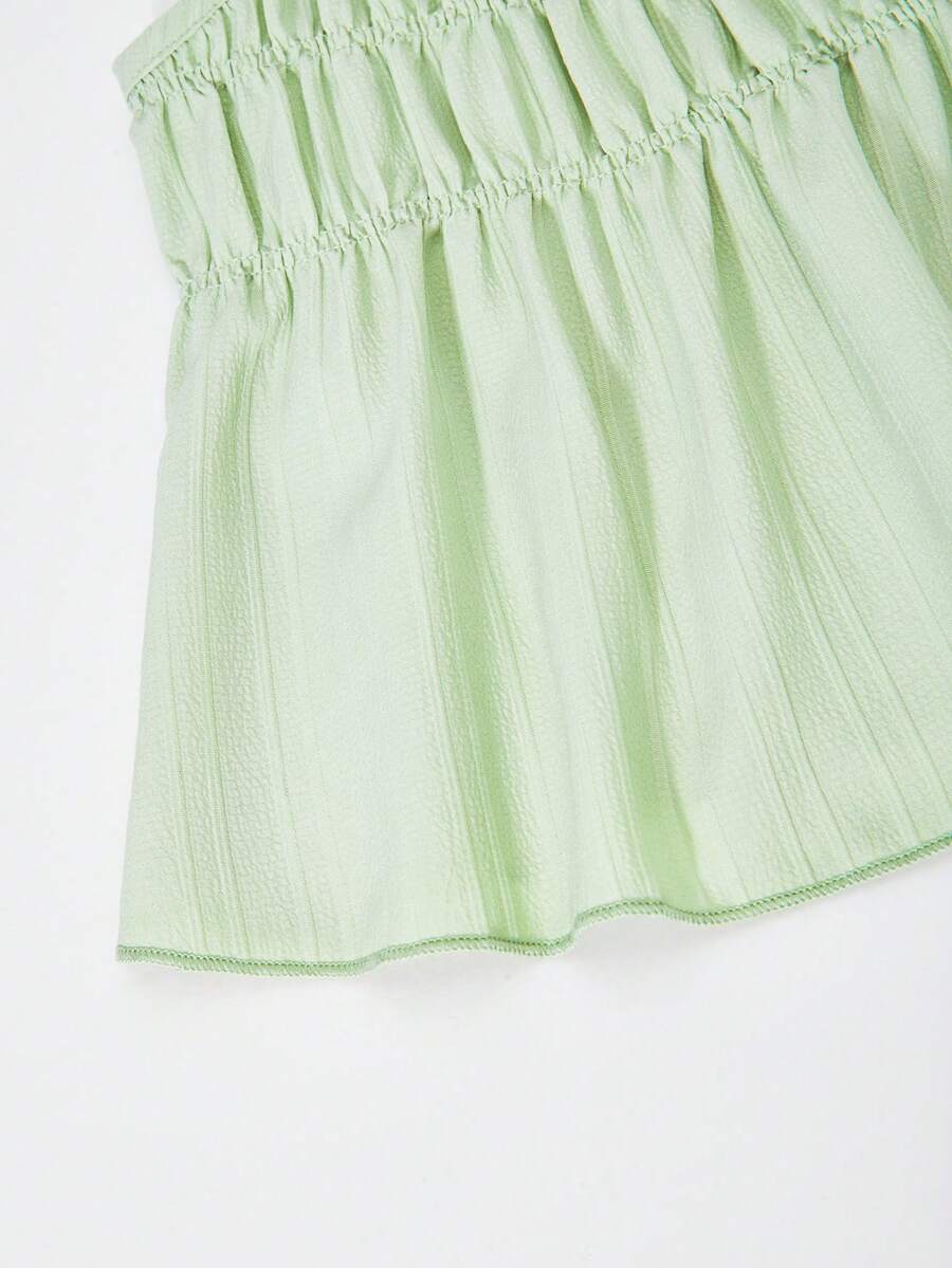 Tween girl wearing an apricot 2-piece outfit set featuring a shirred spaghetti strap short cami top and matching wide-leg long pants.