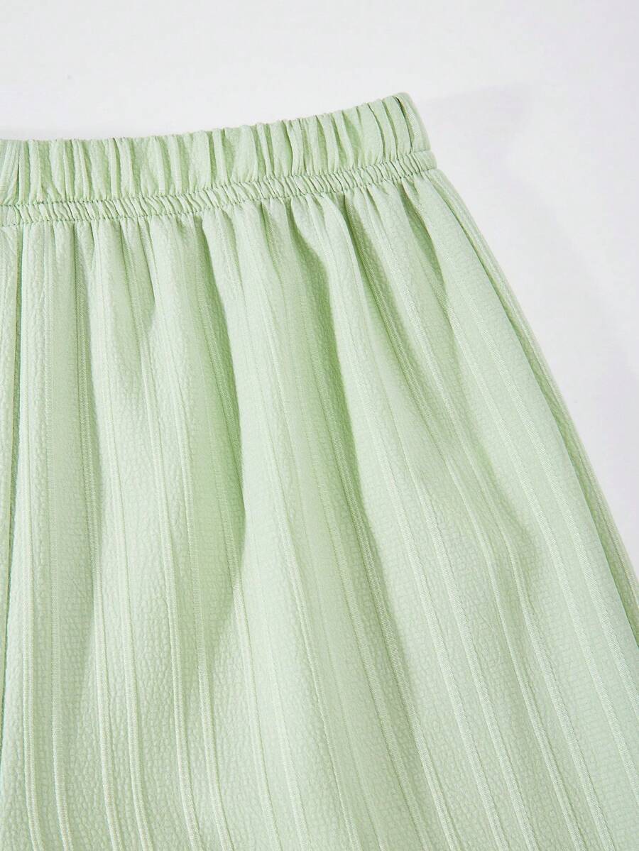 Tween girl wearing an apricot 2-piece outfit set featuring a shirred spaghetti strap short cami top and matching wide-leg long pants.
