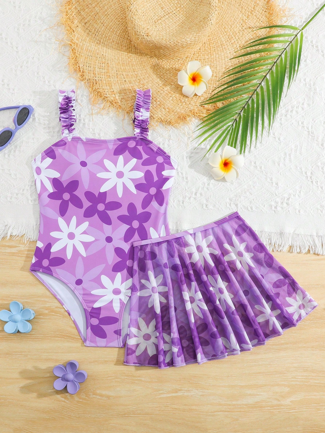 Blue tween girls one-piece swimsuit with tropical plant print, spaghetti straps, ruffle detail, and skirt-style mid-waist bottom for beach and pool wear.