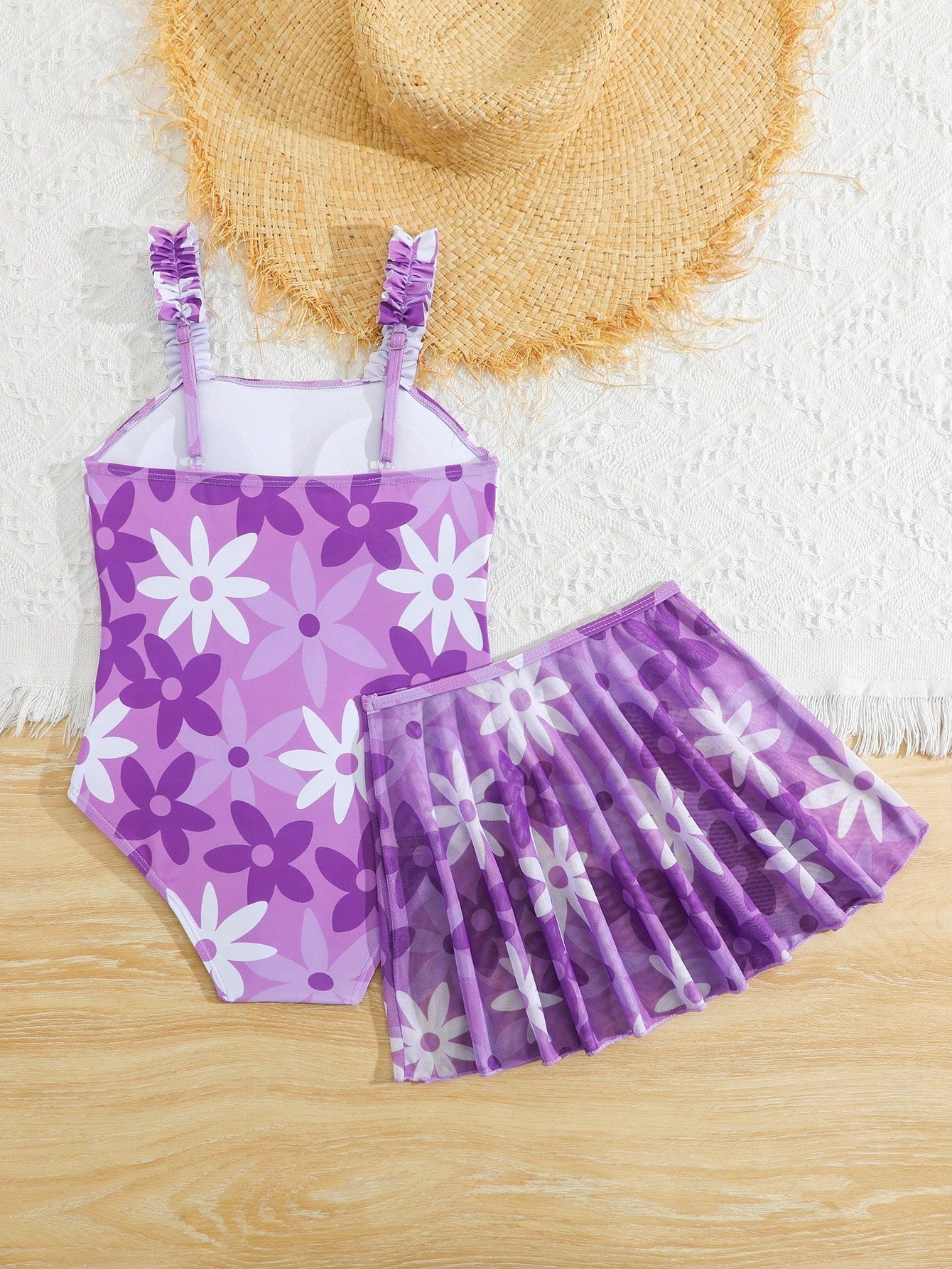 Blue tween girls one-piece swimsuit with tropical plant print, spaghetti straps, ruffle detail, and skirt-style mid-waist bottom for beach and pool wear.