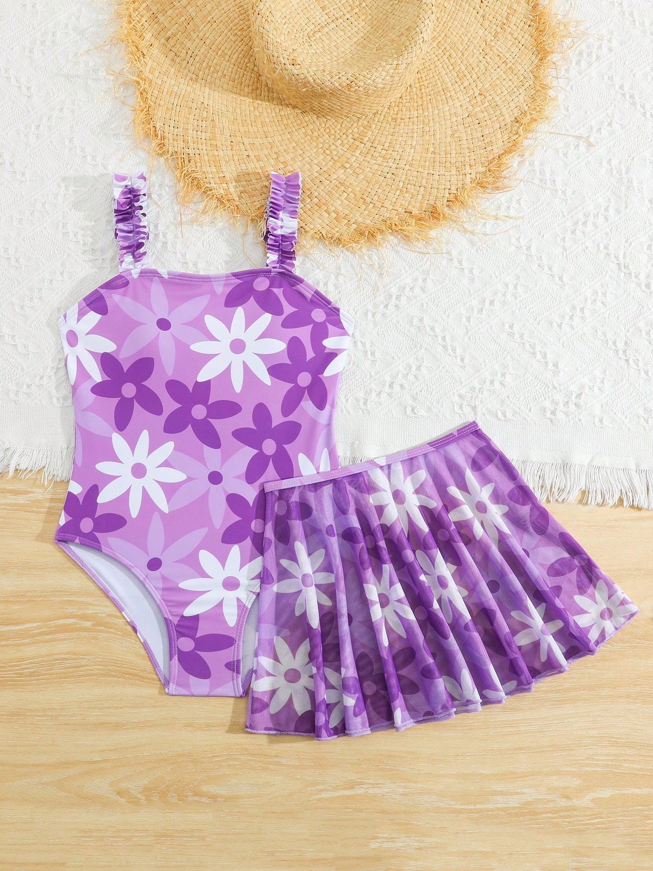 Blue tween girls one-piece swimsuit with tropical plant print, spaghetti straps, ruffle detail, and skirt-style mid-waist bottom for beach and pool wear.