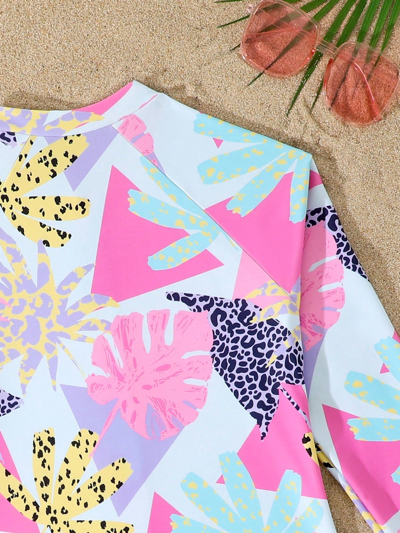 Girls one-piece swimsuit in blue with all-over leopard leaf print, ruffle detail, zipper front, high neck, and lined body for swimming and vacation.