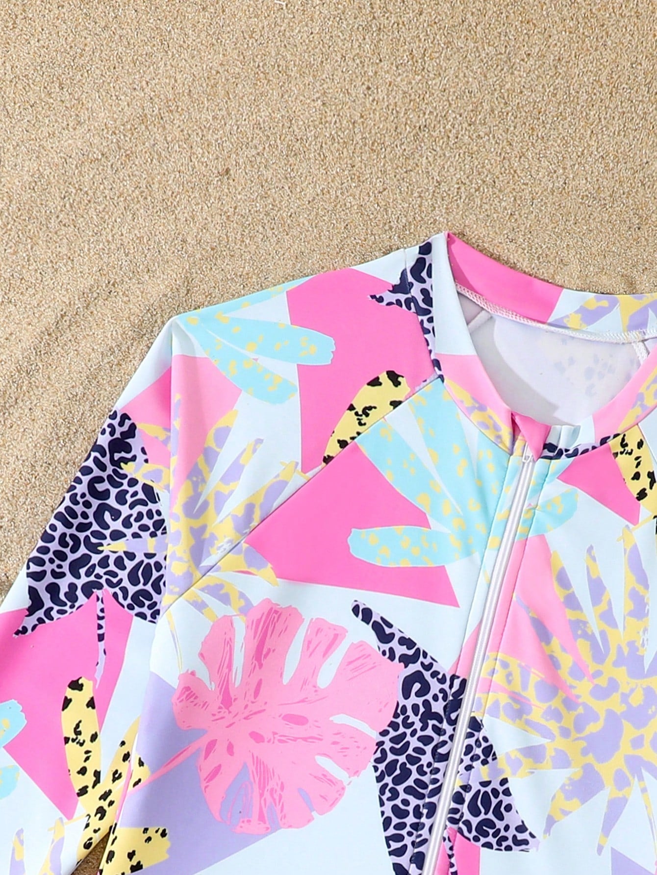 Girls one-piece swimsuit in blue with all-over leopard leaf print, ruffle detail, zipper front, high neck, and lined body for swimming and vacation.