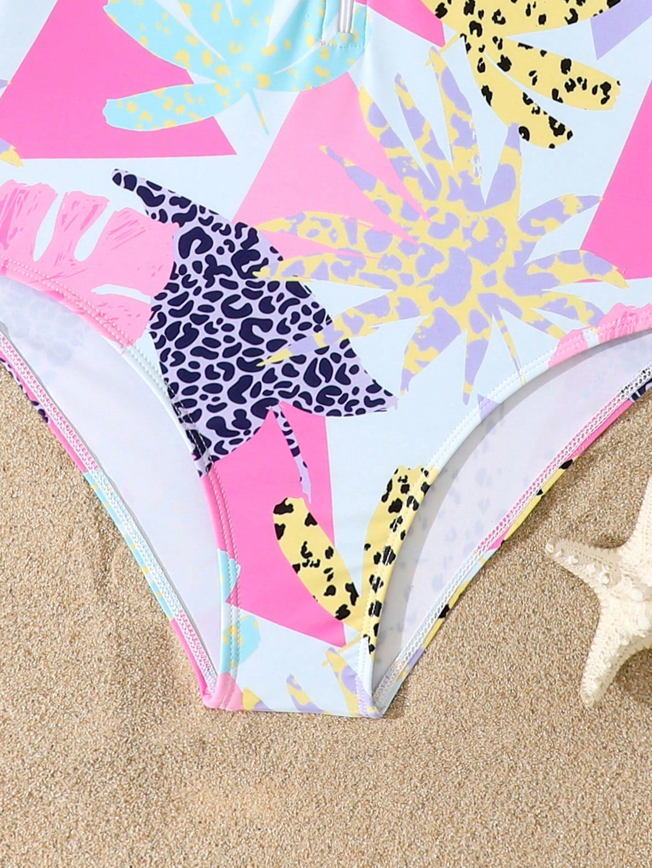 Girls one-piece swimsuit in blue with all-over leopard leaf print, ruffle detail, zipper front, high neck, and lined body for swimming and vacation.
