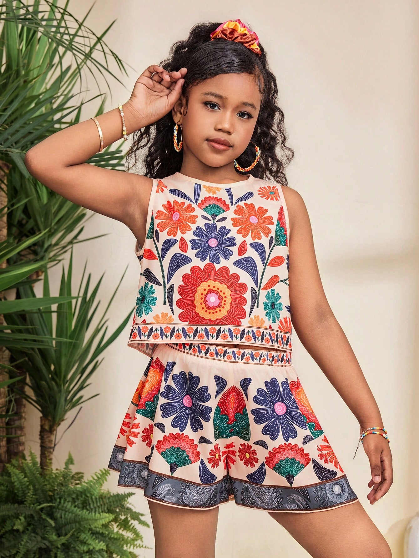 Tween girl wearing a tropical floral print two-piece vacation set featuring a sleeveless round neck tank top with button details and matching shorts.