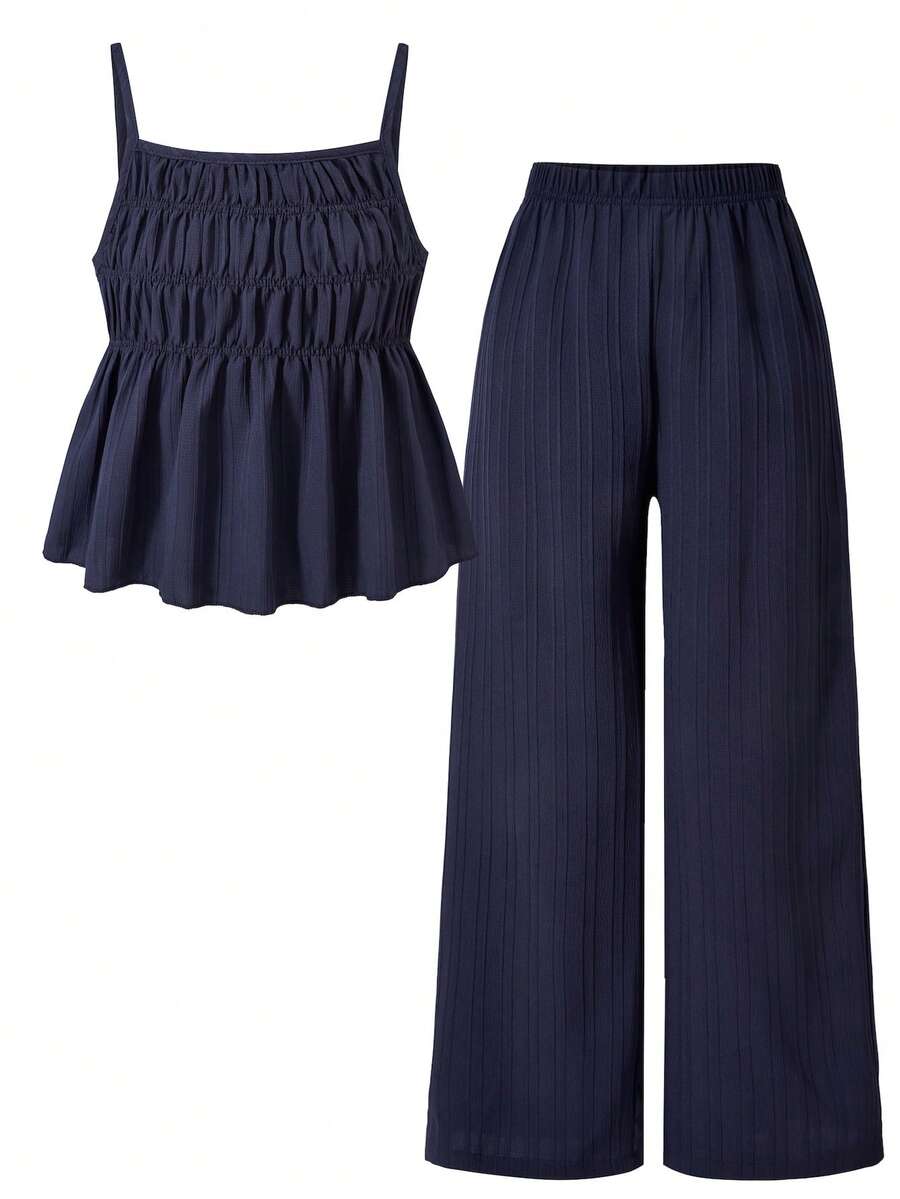 Tween girl wearing an apricot 2-piece outfit set featuring a shirred spaghetti strap short cami top and matching wide-leg long pants.