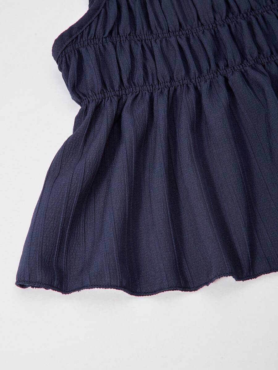 Tween girl wearing an apricot 2-piece outfit set featuring a shirred spaghetti strap short cami top and matching wide-leg long pants.