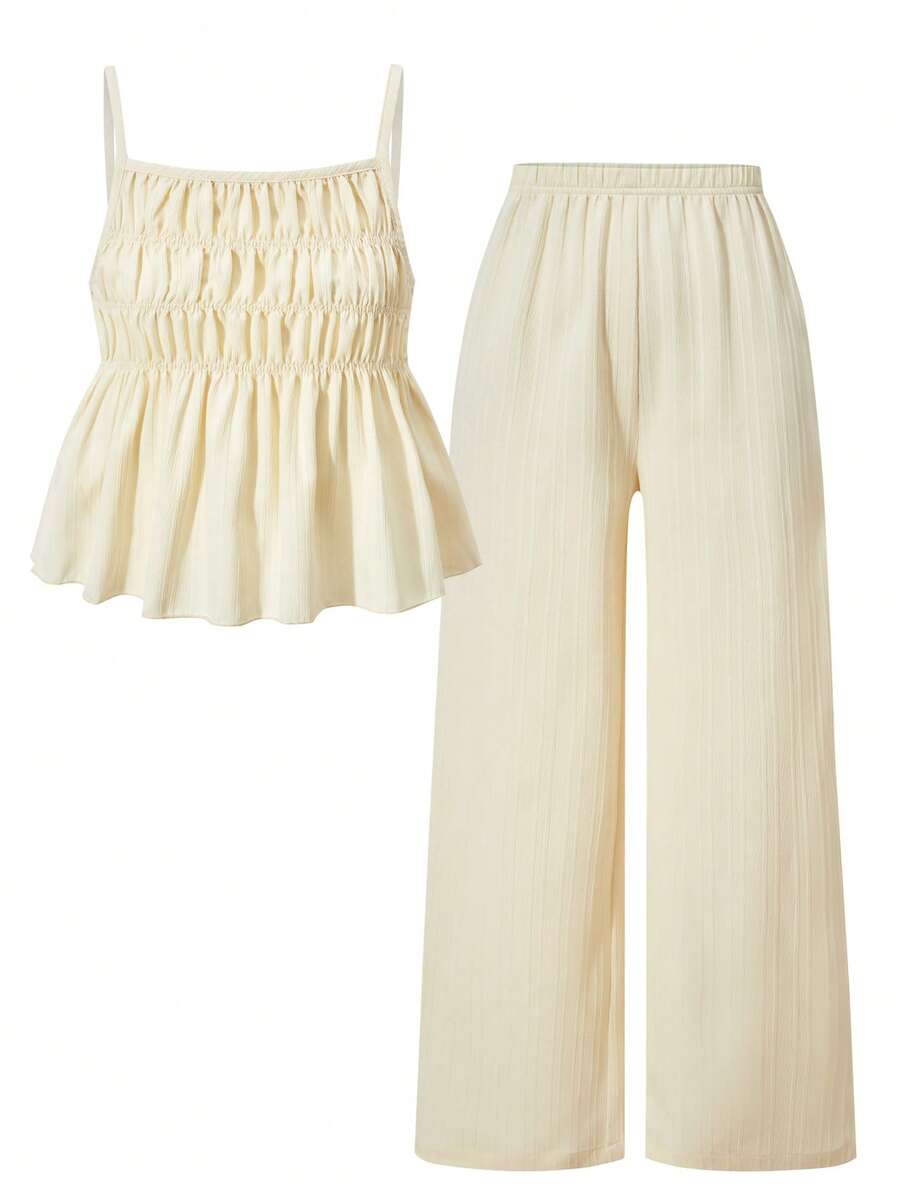 Tween girl wearing an apricot 2-piece outfit set featuring a shirred spaghetti strap short cami top and matching wide-leg long pants.