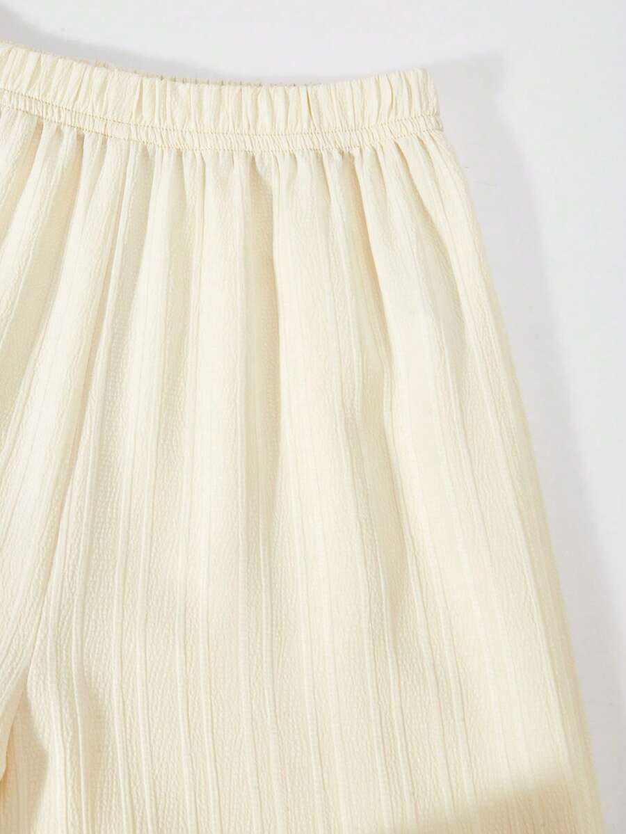 Tween girl wearing an apricot 2-piece outfit set featuring a shirred spaghetti strap short cami top and matching wide-leg long pants.
