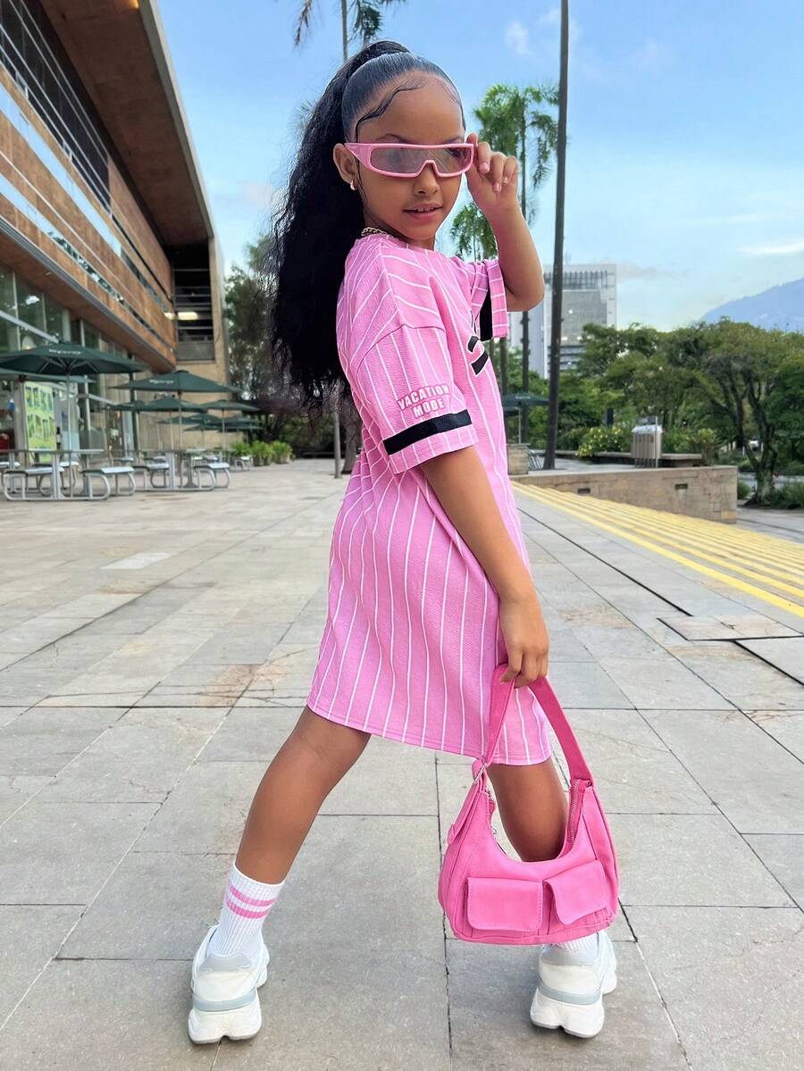 Tween girl wearing a pink streetwear oversized short sleeve t-shirt dress featuring a round neck, drop shoulders, and pleated split details.