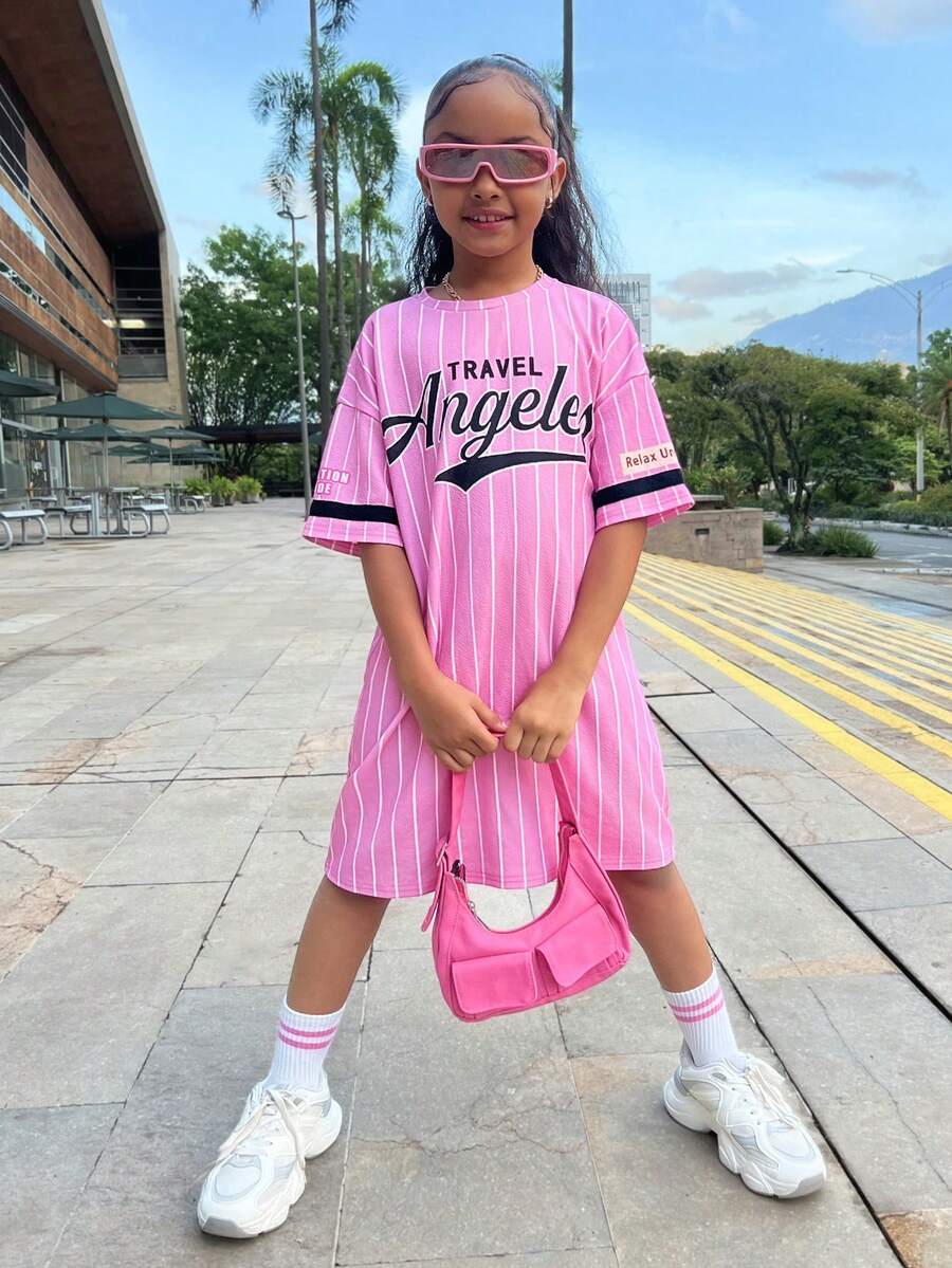 Tween girl wearing a pink streetwear oversized short sleeve t-shirt dress featuring a round neck, drop shoulders, and pleated split details.