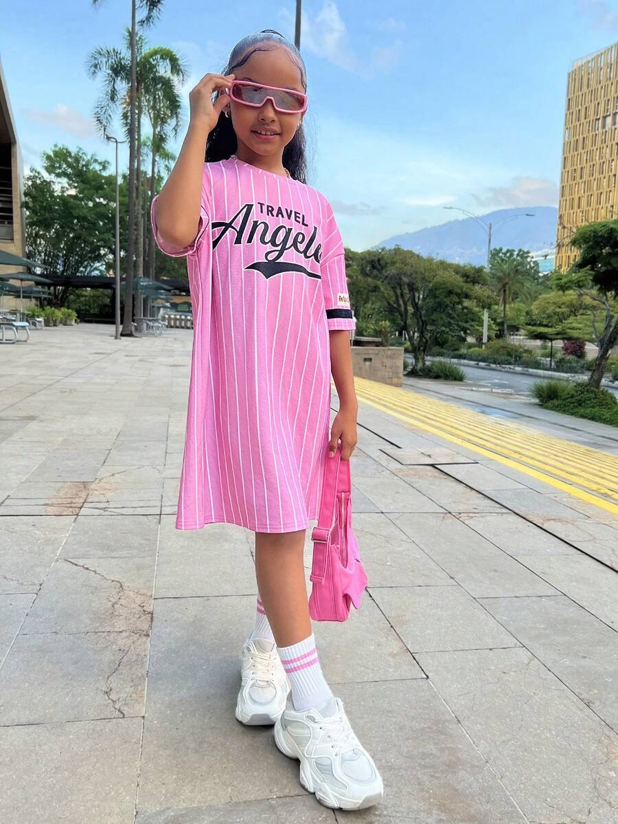 Tween girl wearing a pink streetwear oversized short sleeve t-shirt dress featuring a round neck, drop shoulders, and pleated split details.