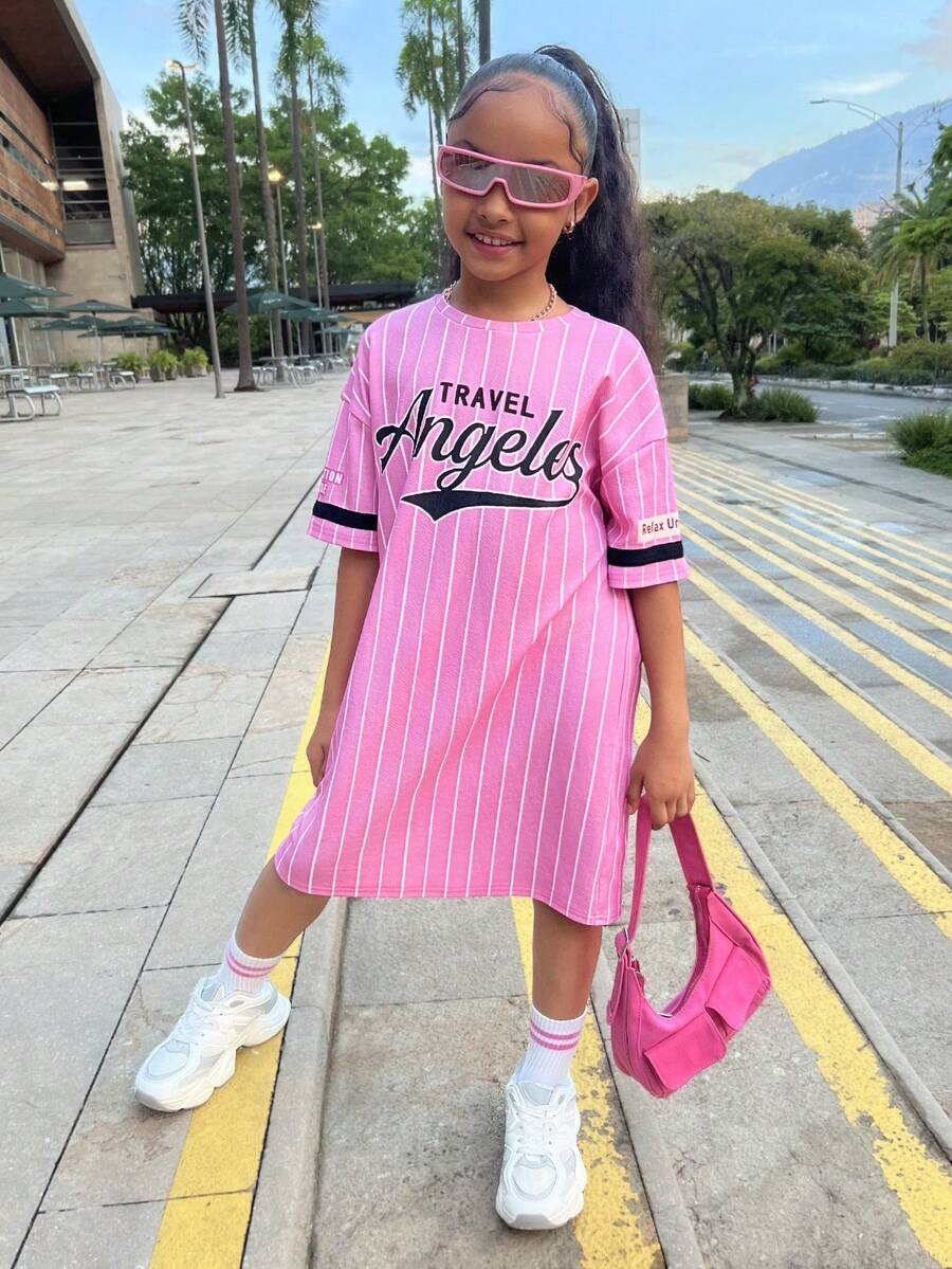 Tween girl wearing a pink streetwear oversized short sleeve t-shirt dress featuring a round neck, drop shoulders, and pleated split details.