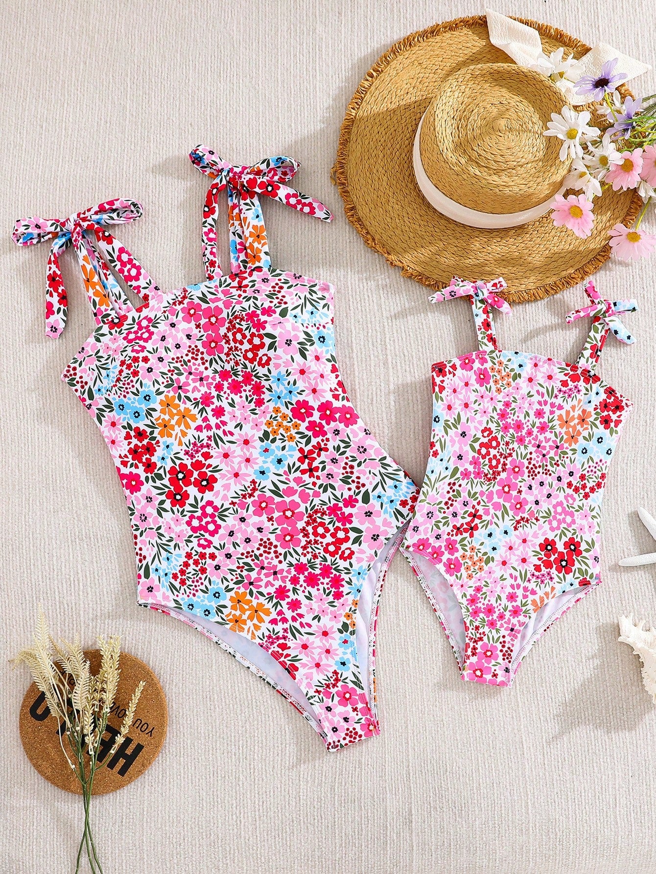 Tween girl floral print one-piece swimsuit with twist front, spaghetti straps, fitted shape, and multicolor all-over hibiscus-inspired pattern for beach and pool wear.