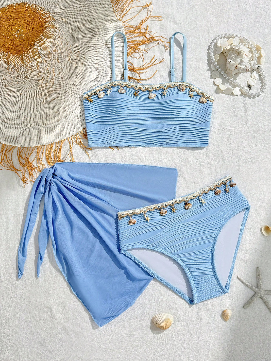 Tween girls bikini set with shell and starfish woven band details, spaghetti strap sleeveless top, and mid-waist skirt-style bottom in blue.