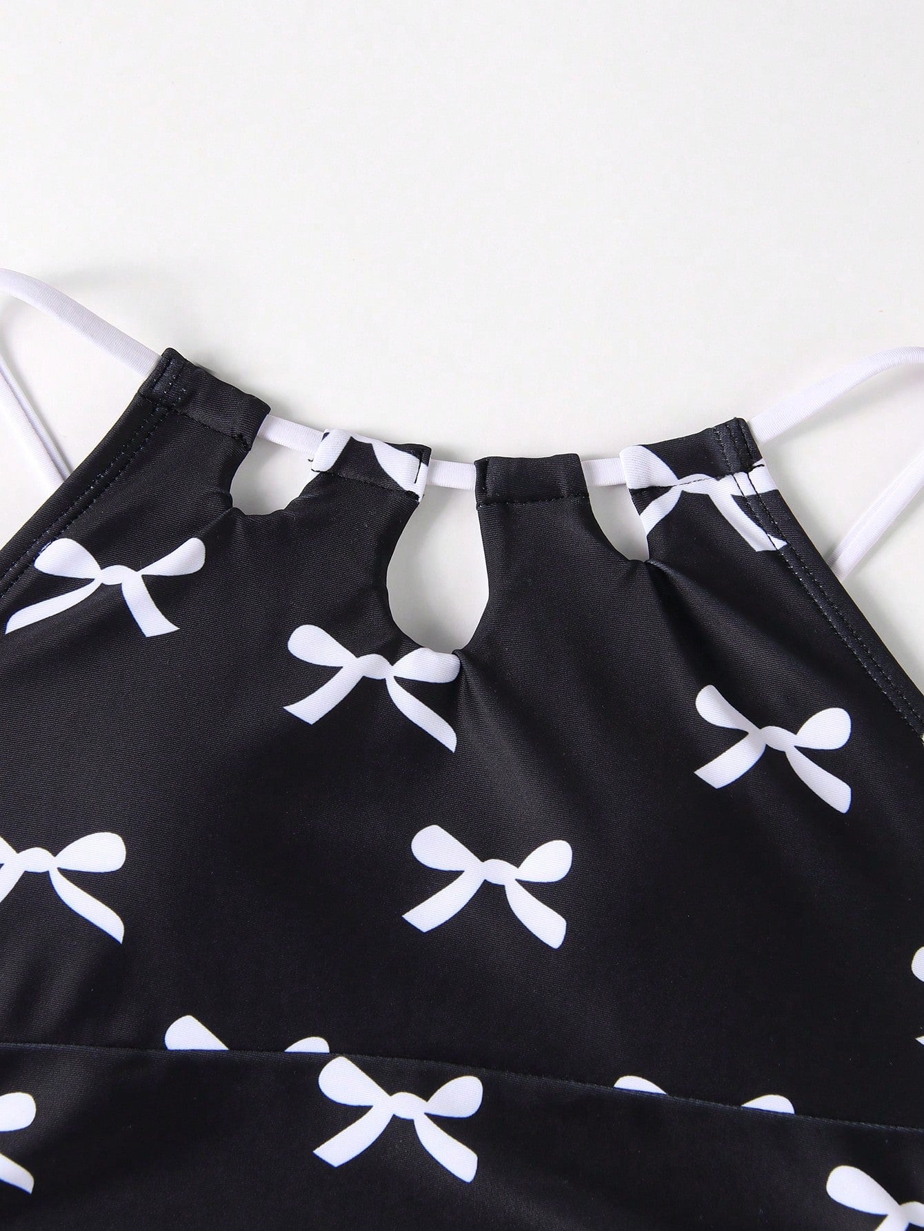 Girls black and white one-piece swimsuit set with cut-out detail, spaghetti straps, sleeveless fitted design, and matching skirt bottom for vacation swimwear.