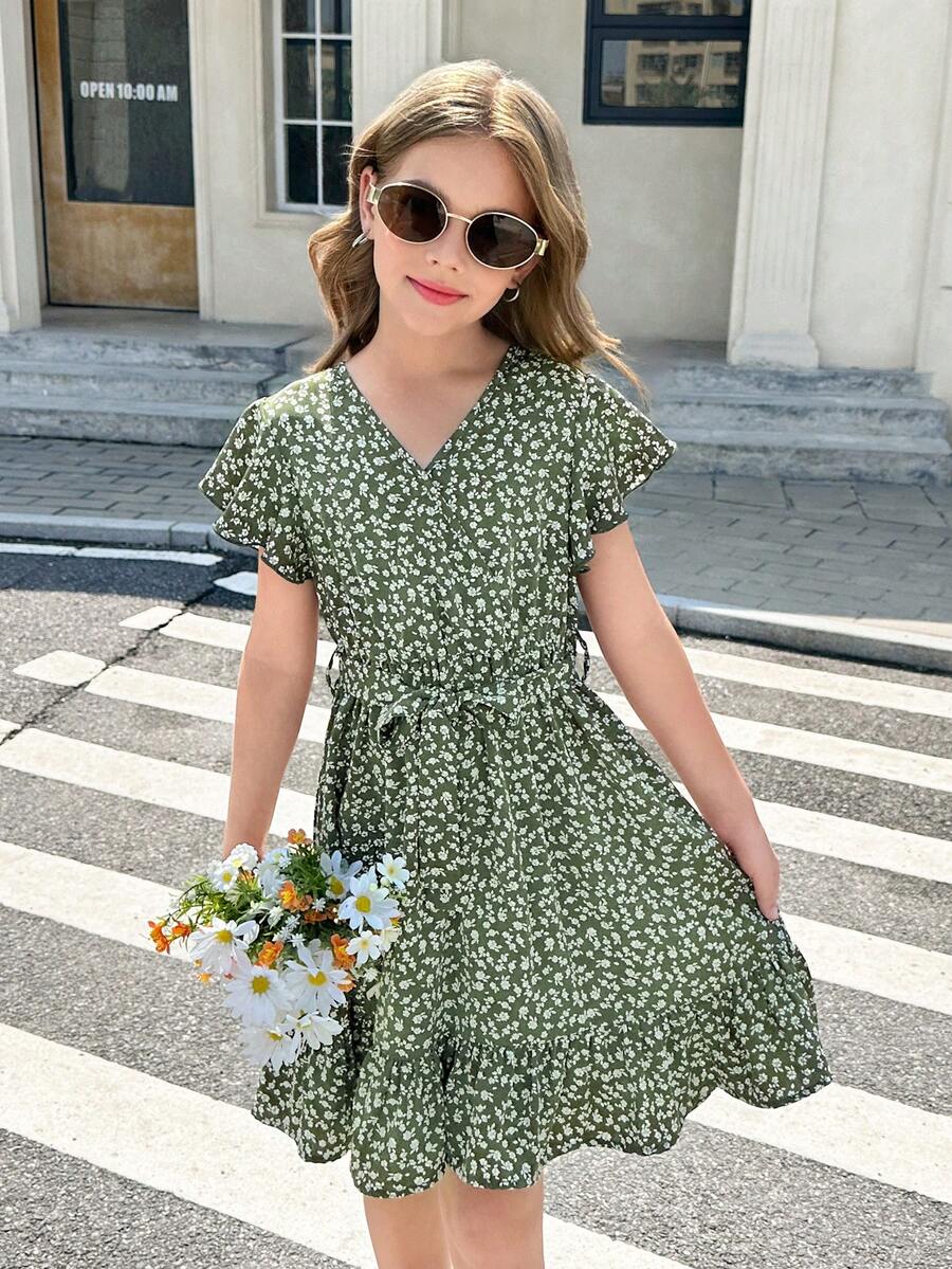Tween girl wearing a black ditsy floral A-line short dress with V-neckline and flounce short sleeves.
