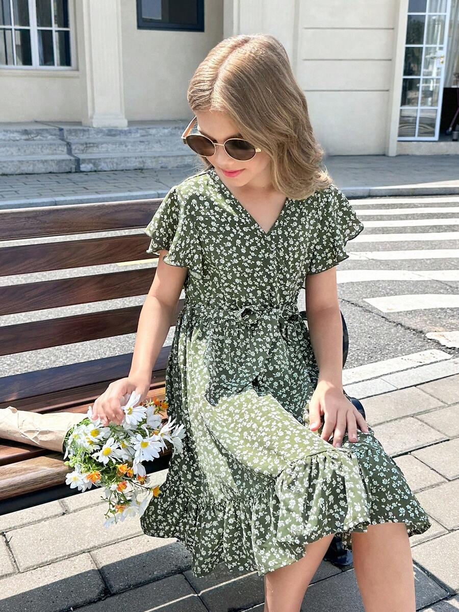 Tween girl wearing a black ditsy floral A-line short dress with V-neckline and flounce short sleeves.