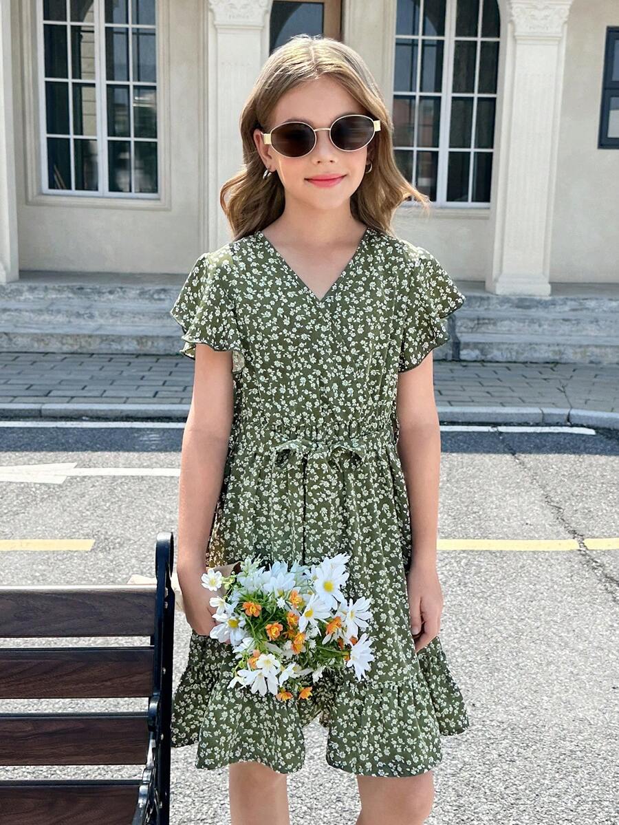 Tween girl wearing a black ditsy floral A-line short dress with V-neckline and flounce short sleeves.