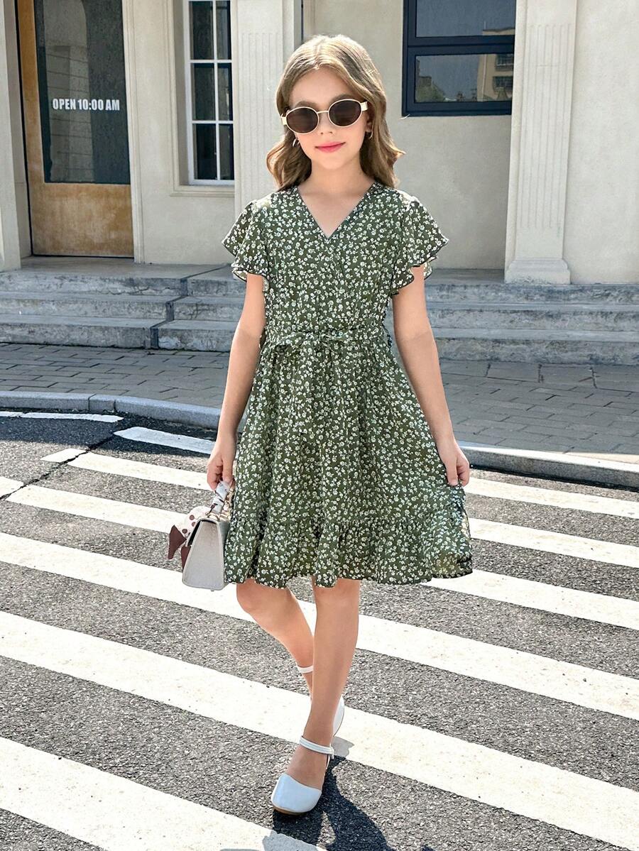 Tween girl wearing a black ditsy floral A-line short dress with V-neckline and flounce short sleeves.