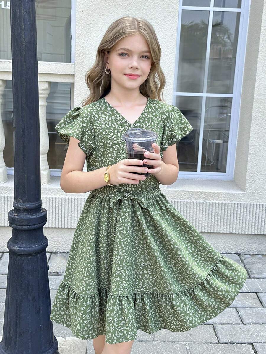 Tween girl wearing a black ditsy floral A-line short dress with V-neckline and flounce short sleeves.
