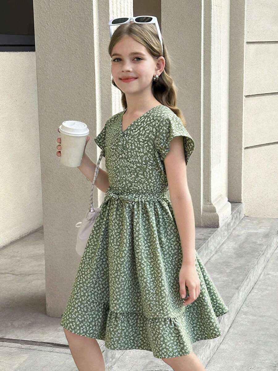 Tween girl wearing a black ditsy floral A-line short dress with V-neckline and flounce short sleeves.