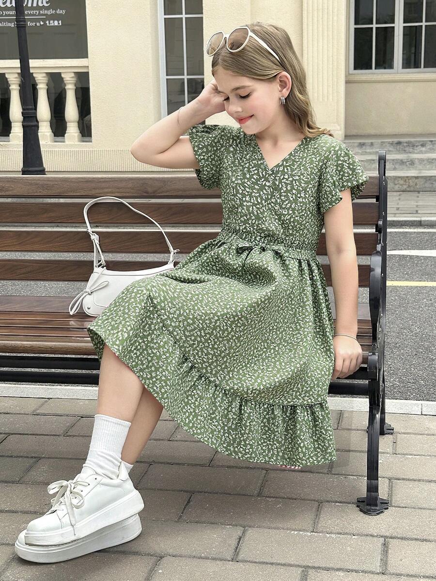 Tween girl wearing a black ditsy floral A-line short dress with V-neckline and flounce short sleeves.