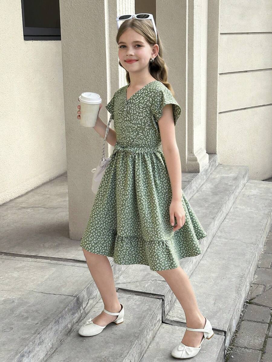 Tween girl wearing a black ditsy floral A-line short dress with V-neckline and flounce short sleeves.