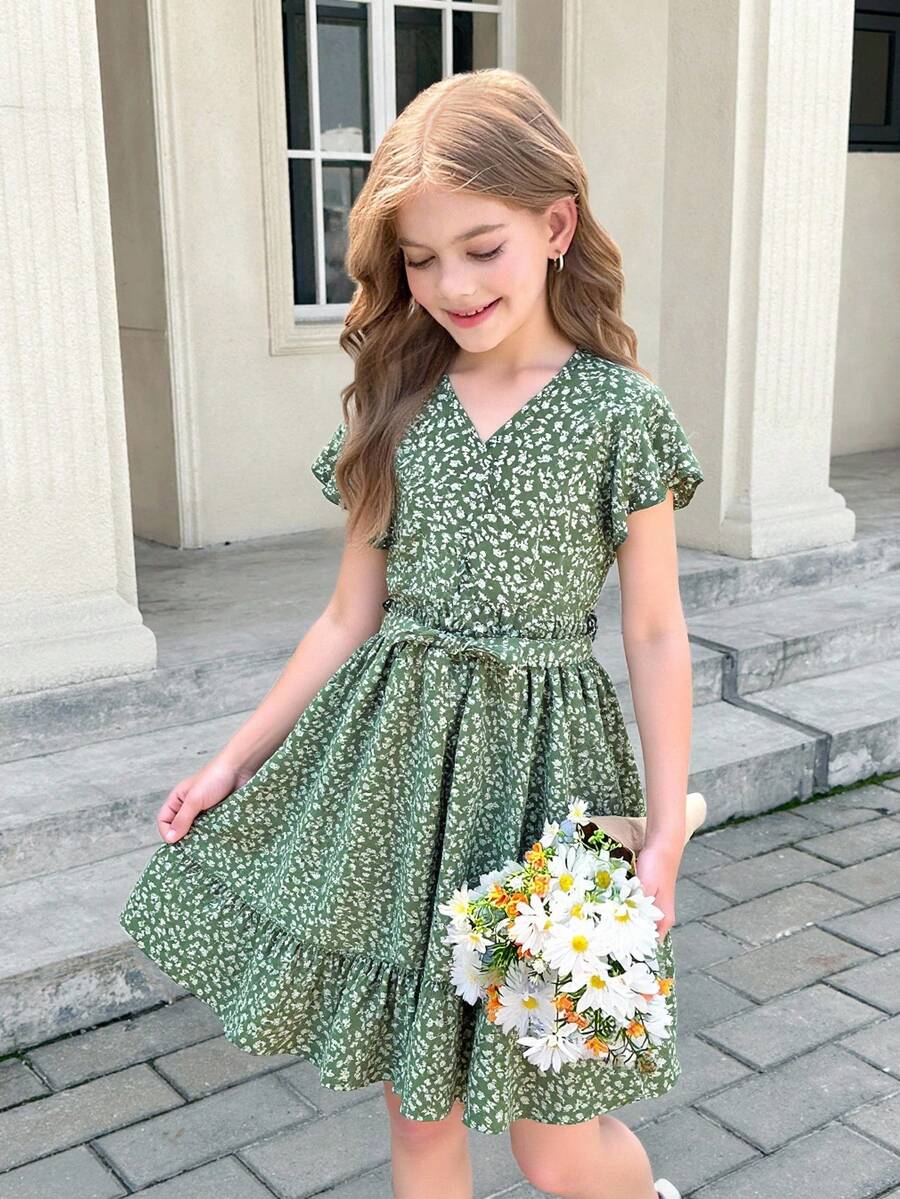 Tween girl wearing a black ditsy floral A-line short dress with V-neckline and flounce short sleeves.