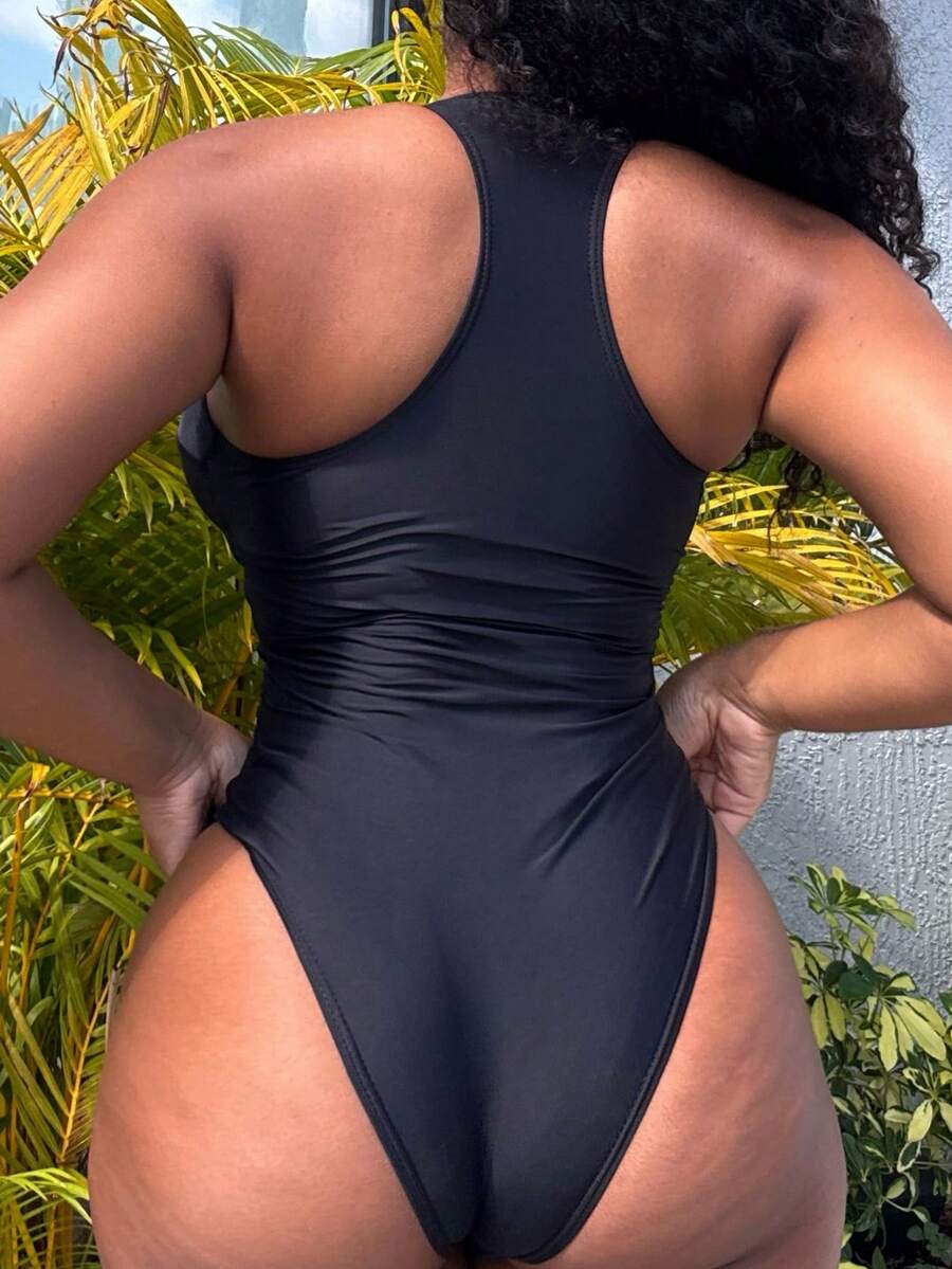 Dark green women's one-piece swimsuit featuring a zipper V-neckline and backless design.