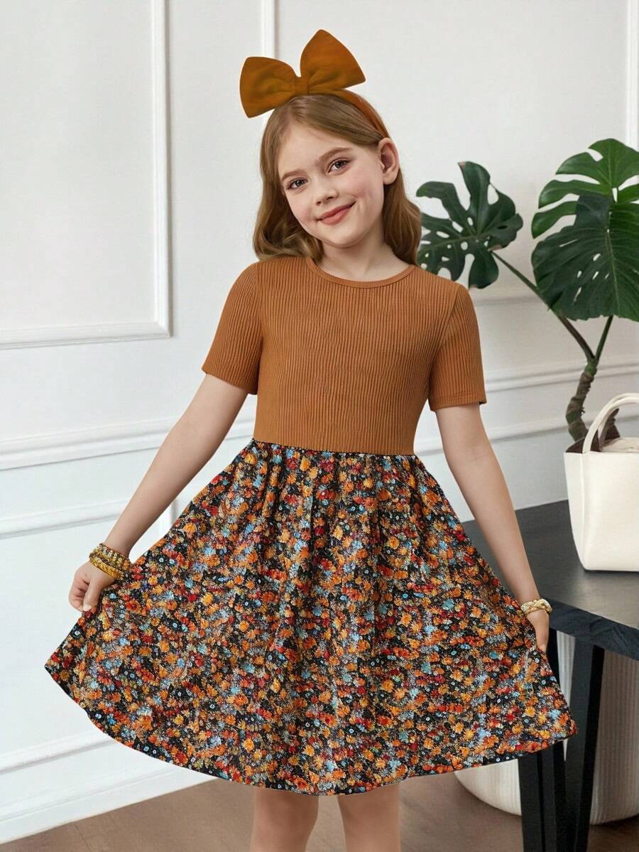Tween girl wearing an apricot short sleeve A-line dress featuring a round neck, high waist with a belt, and flared hem.
