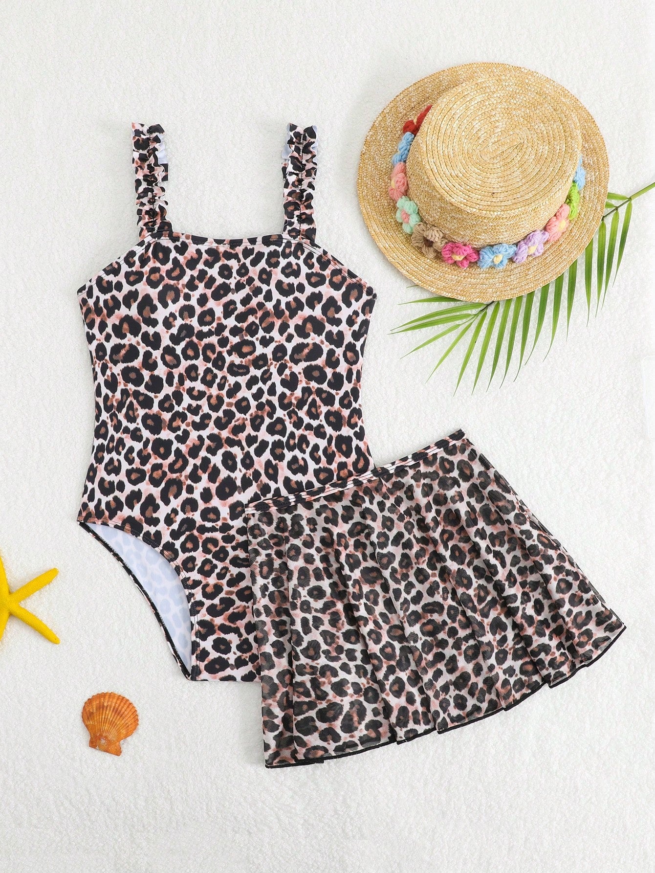 Blue tween girls one-piece swimsuit with tropical plant print, spaghetti straps, ruffle detail, and skirt-style mid-waist bottom for beach and pool wear.