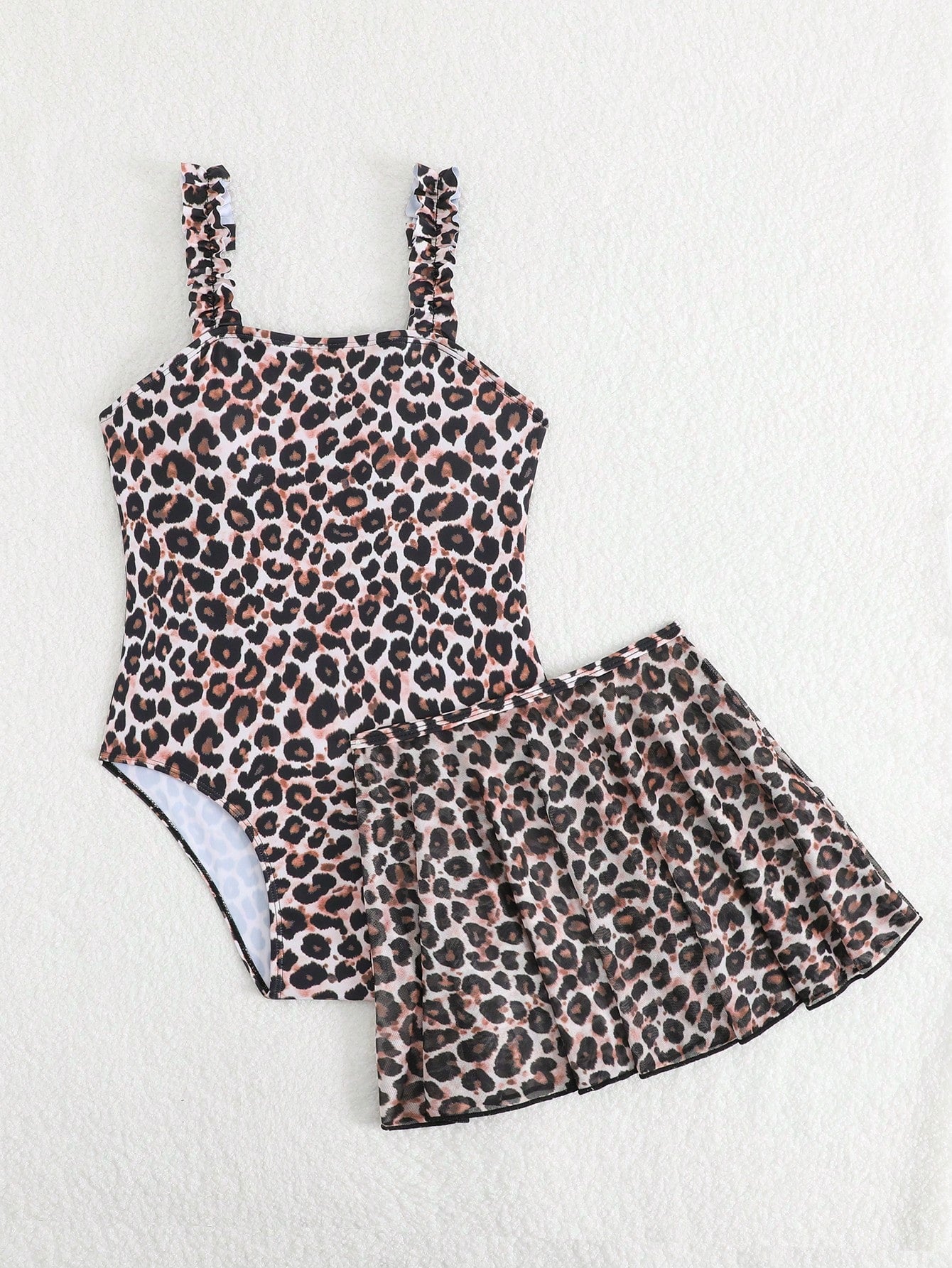 Blue tween girls one-piece swimsuit with tropical plant print, spaghetti straps, ruffle detail, and skirt-style mid-waist bottom for beach and pool wear.