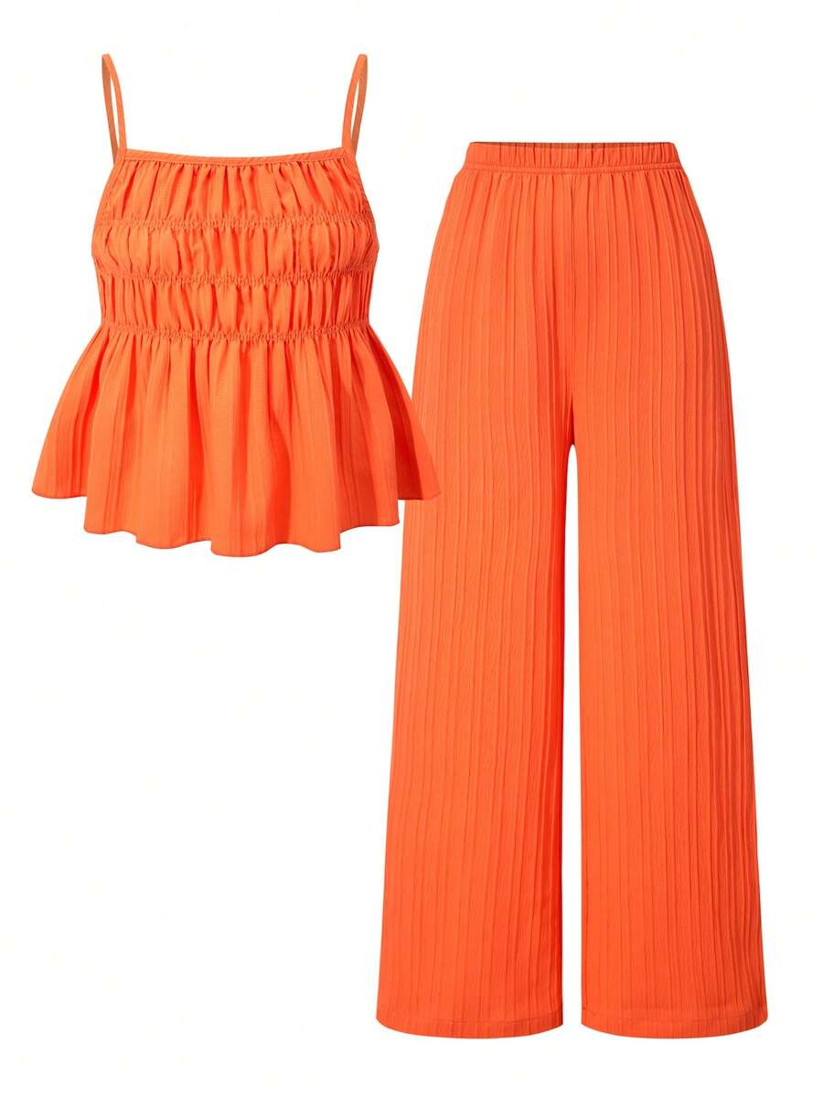 Tween girl wearing an apricot 2-piece outfit set featuring a shirred spaghetti strap short cami top and matching wide-leg long pants.