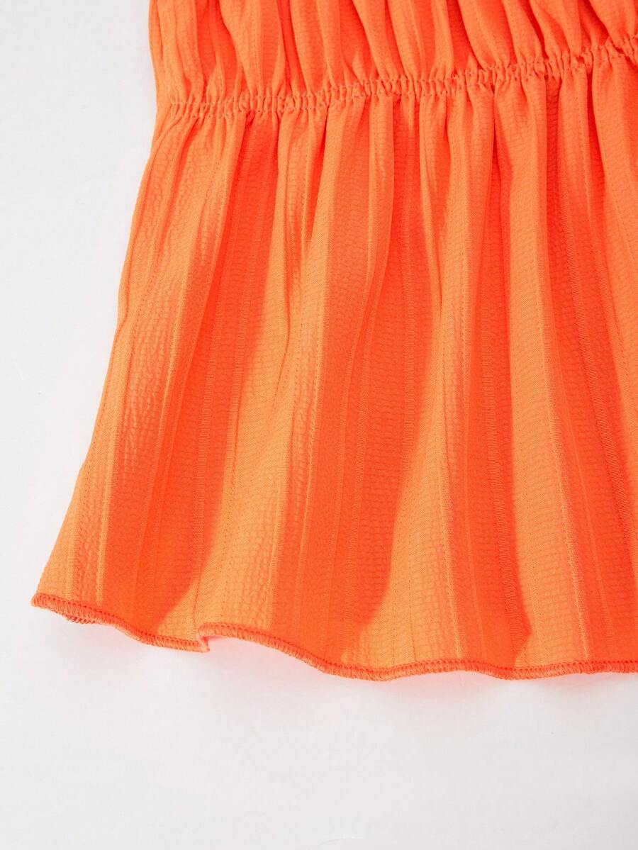 Tween girl wearing an apricot 2-piece outfit set featuring a shirred spaghetti strap short cami top and matching wide-leg long pants.
