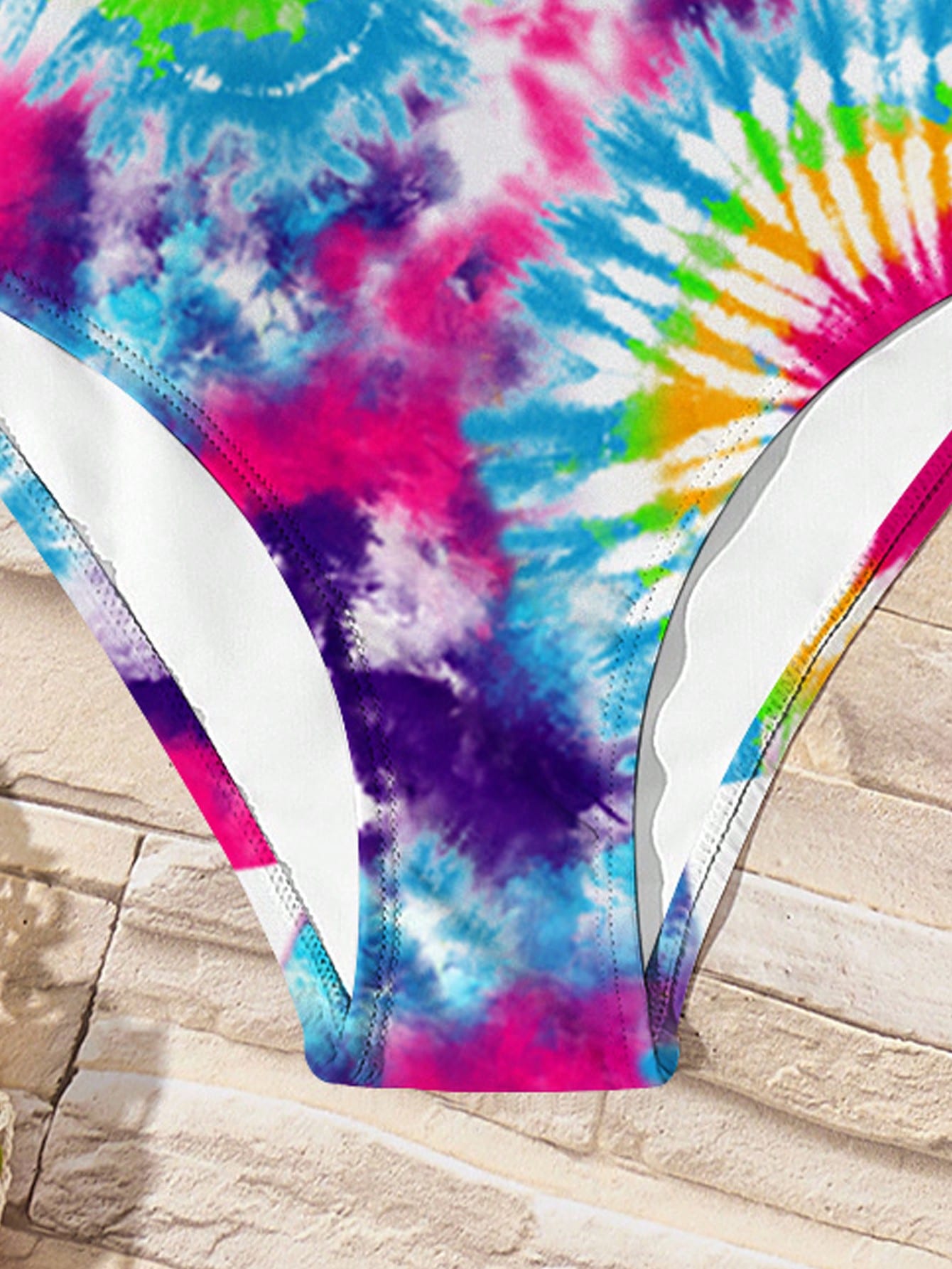 Tween girls multicolor one-piece swimsuit with cut-out detail, spaghetti straps, all-over tie-dye style print, and natural mid-waist bottom for beach and vacation wear.