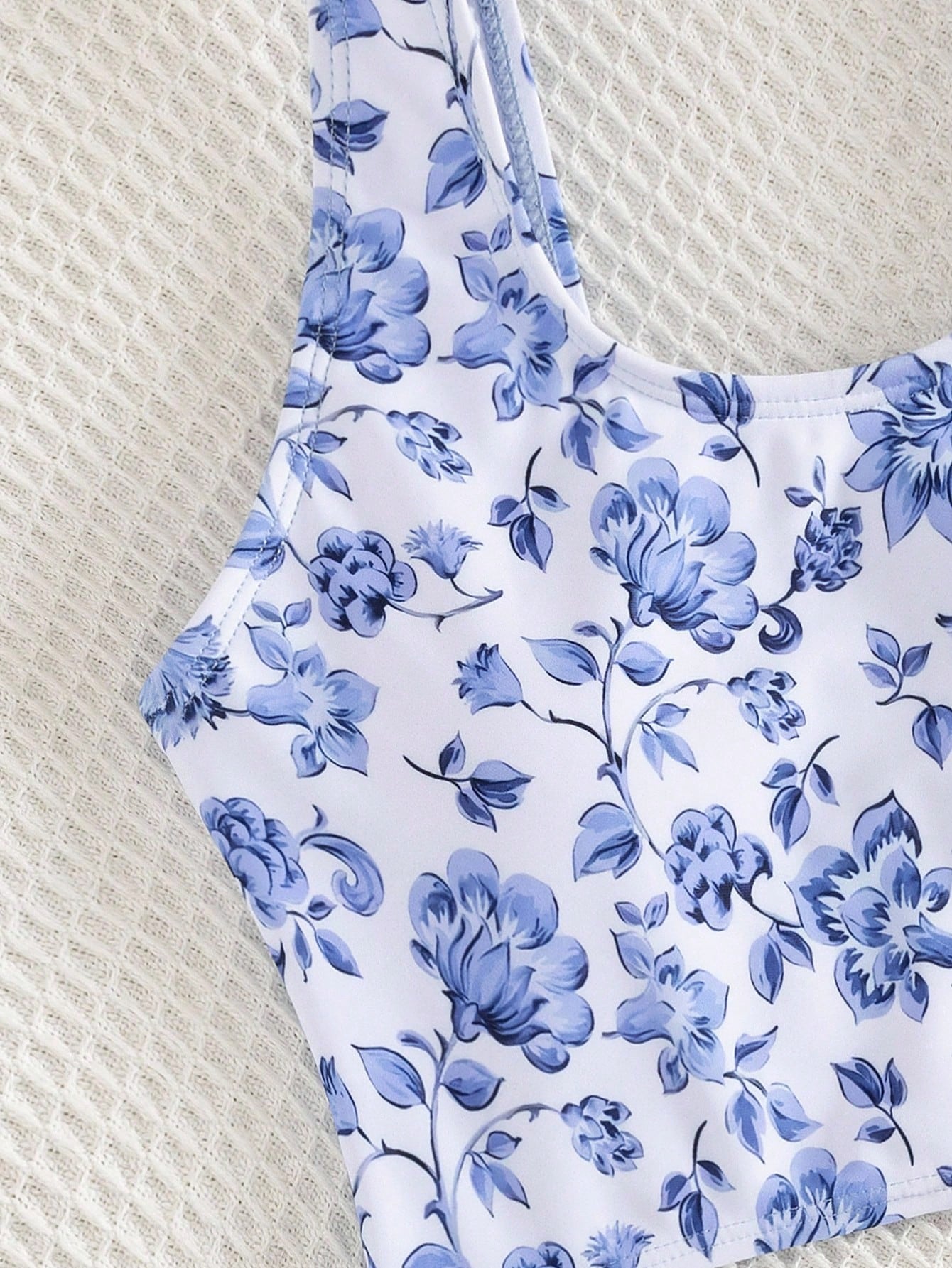 Tween girls blue and white floral one-piece swimsuit with scoop neck, cut-out detail, lined body, and high-stretch fabric for beach and vacation wear.