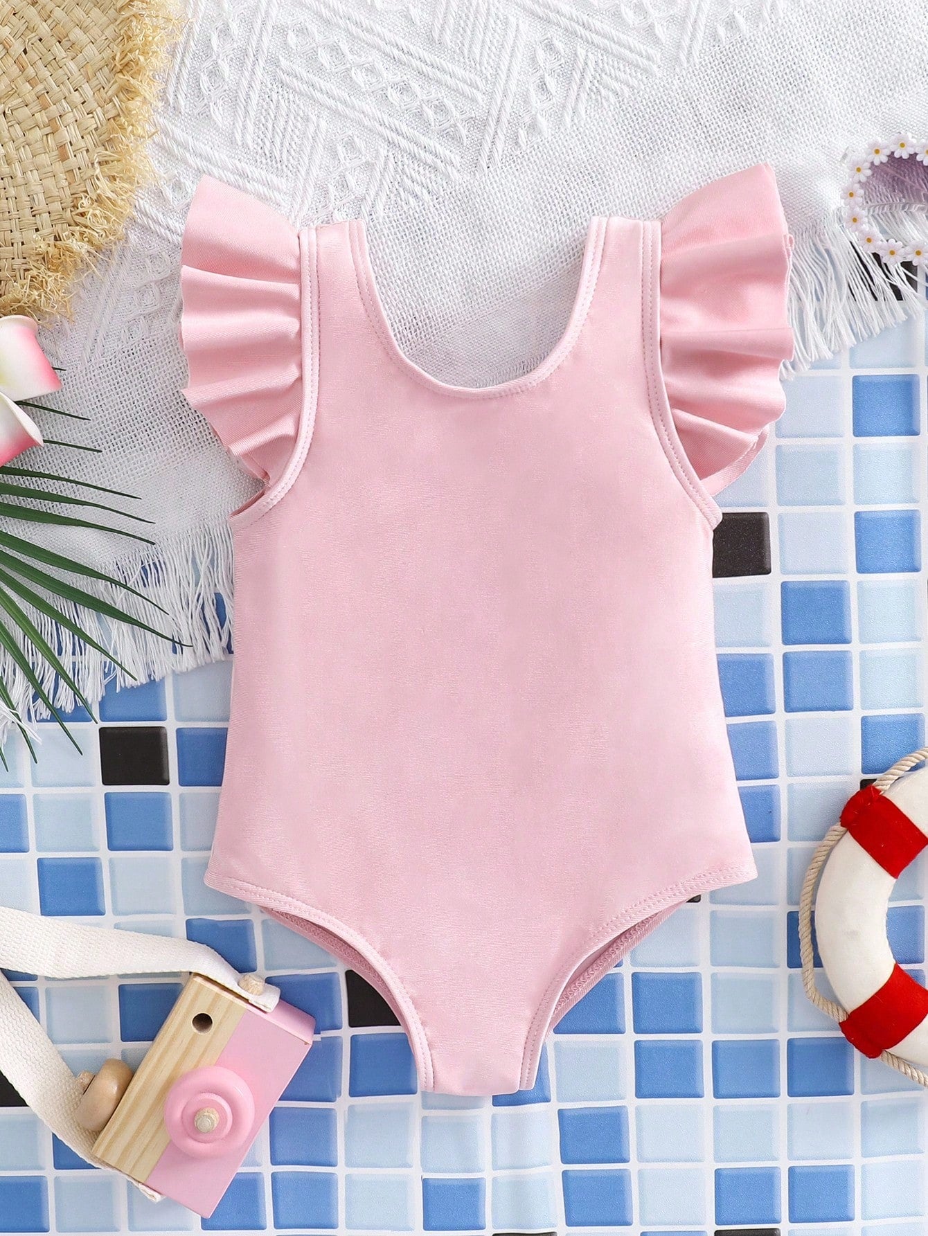 Baby pink colorblock one-piece swimsuit for tween girls with ruffle details, bow decor, scoop neckline, and fitted vacation swimwear style.
