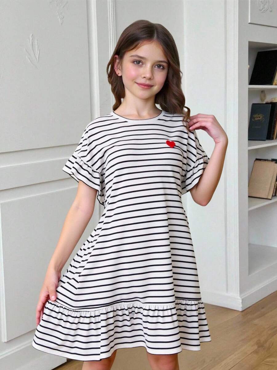 Black and white tween girls smock dress featuring a round neck, heart pattern, embroidered details, and a flounce hem.