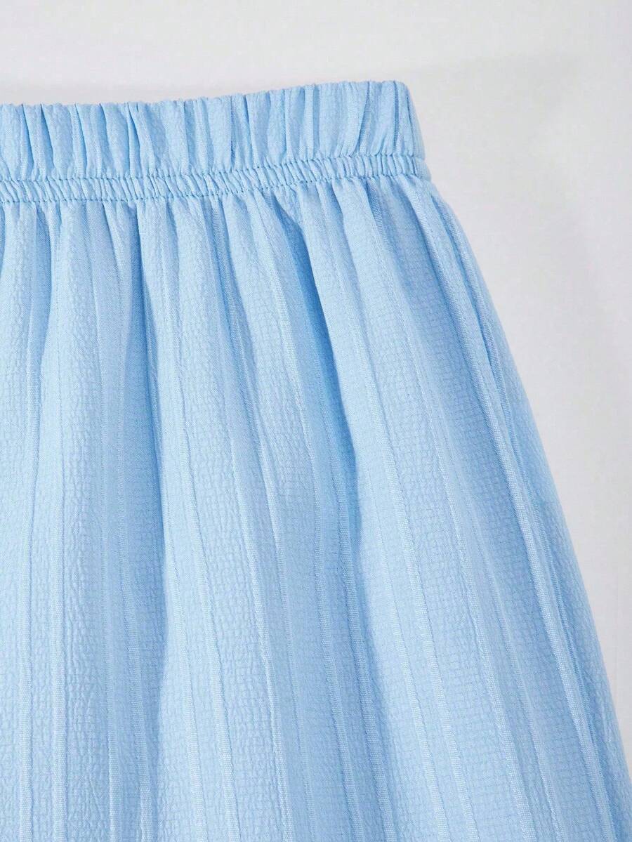 Tween girl wearing an apricot 2-piece outfit set featuring a shirred spaghetti strap short cami top and matching wide-leg long pants.