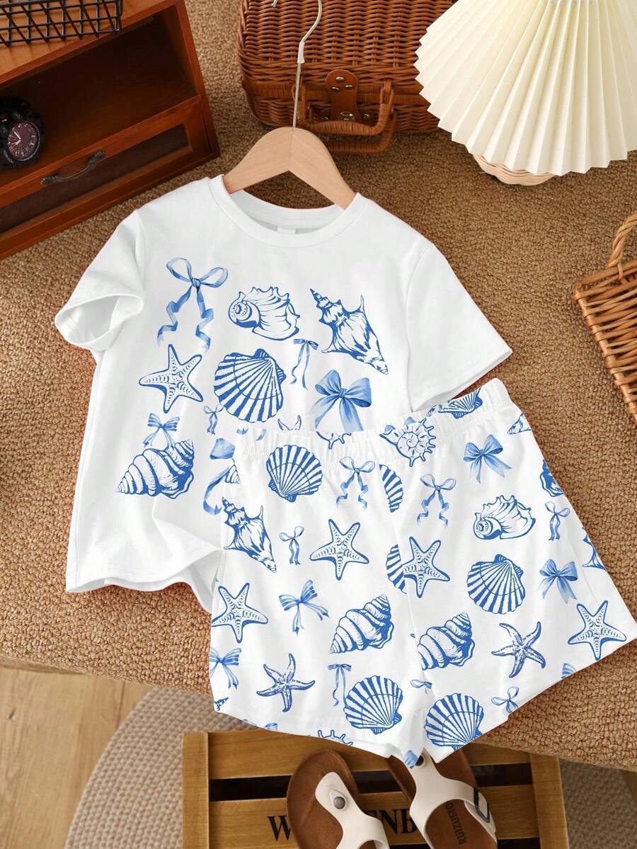 Teen girl wearing 2-piece summer vacation set with blue and white striped short sleeve top featuring seashell ocean bow print and matching loose fit shorts with pockets.
