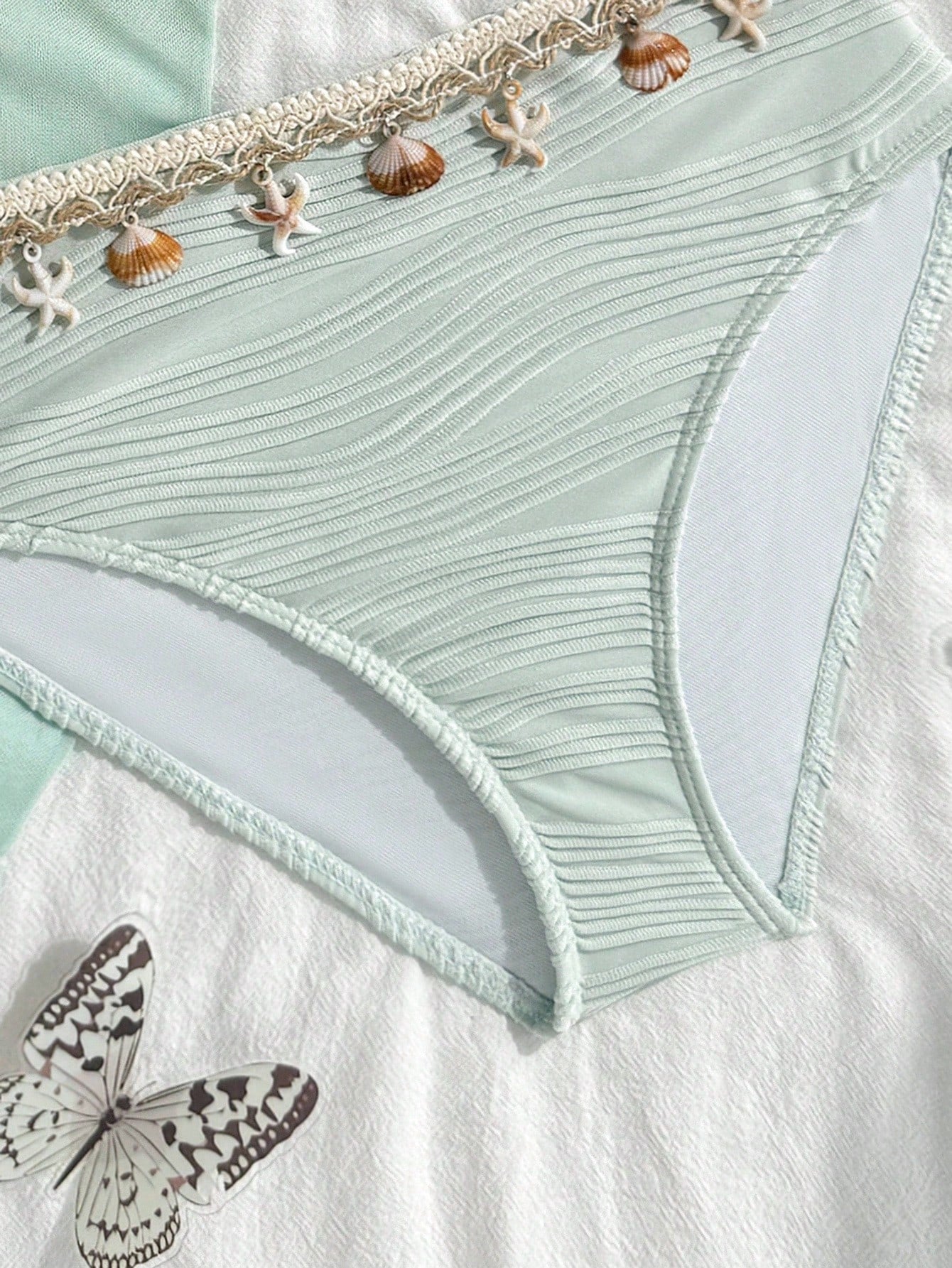 Tween girls bikini set with shell and starfish woven band details, spaghetti strap sleeveless top, and mid-waist skirt-style bottom in blue.