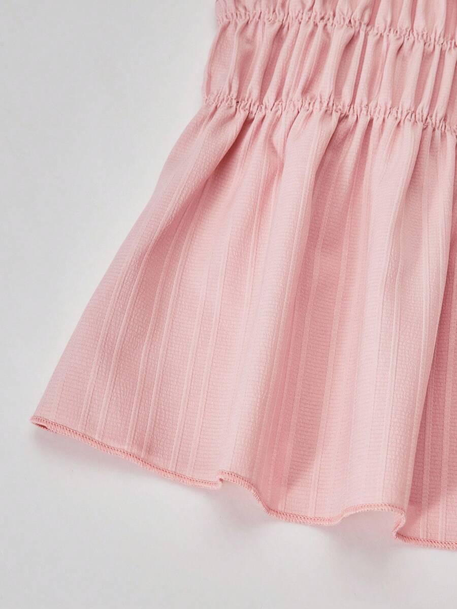 Tween girl wearing an apricot 2-piece outfit set featuring a shirred spaghetti strap short cami top and matching wide-leg long pants.