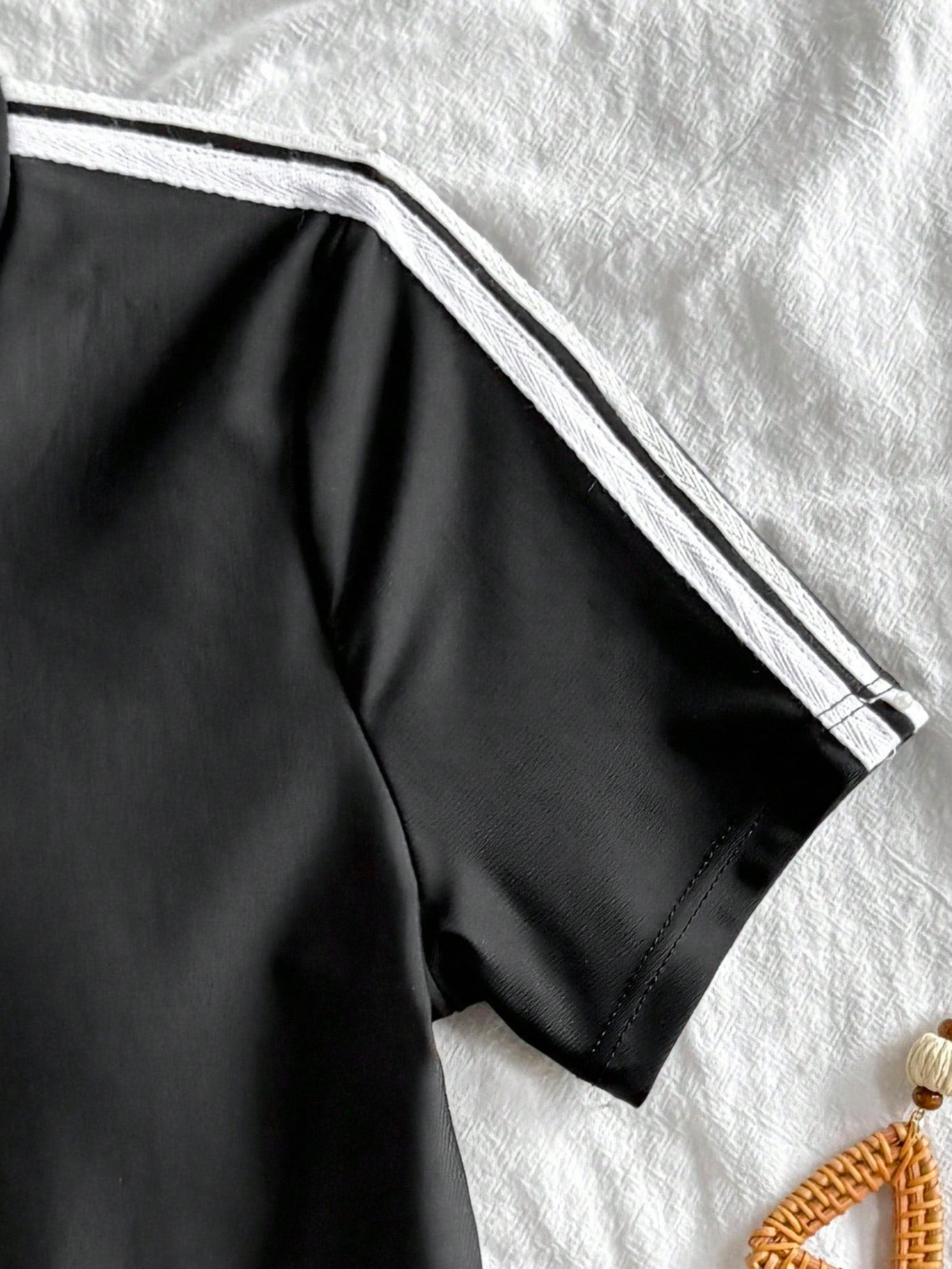 Black and white one-piece rashguard swimsuit for tween girls with short sleeves, high neck, zipper detail, fitted shape, and shorts-style bottom.