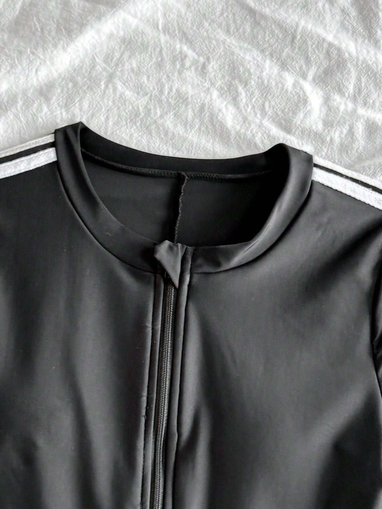Black and white one-piece rashguard swimsuit for tween girls with short sleeves, high neck, zipper detail, fitted shape, and shorts-style bottom.